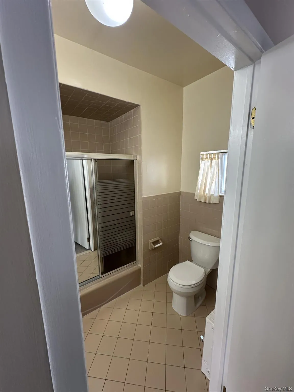 Bathroom with tile walls, light tile patterned floors, and wainscoting Bathroom with tile walls, light tile patterned floors, and wainscoting