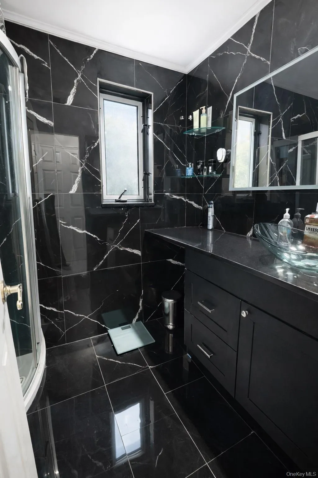 Full bathroom with vanity, a marble finish shower, tile walls, and crown molding Full bathroom with vanity, a marble finish shower, tile walls, and crown molding