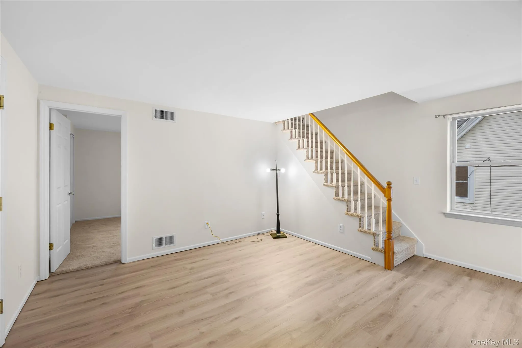 Unfurnished living room featuring stairs and light wood-type flooring Unfurnished living room featuring stairs and light wood-type flooring