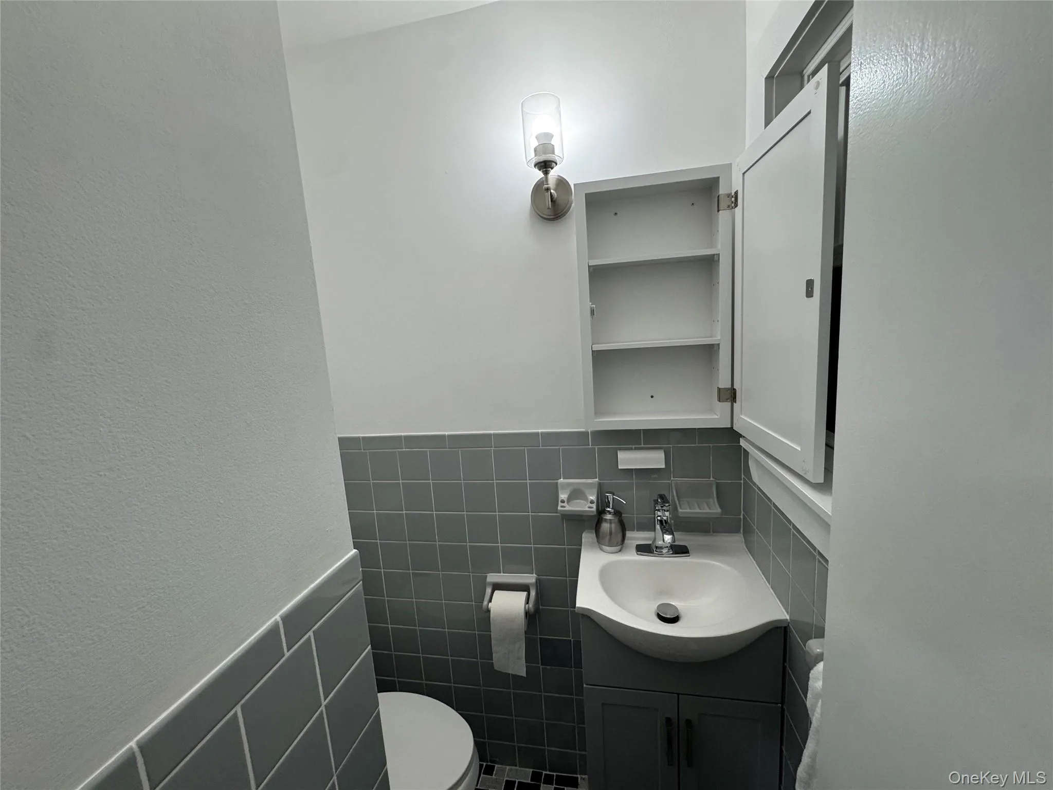 Half bathroom featuring tile walls, a wainscoted wall, and vanity Half bathroom featuring tile walls, a wainscoted wall, and vanity