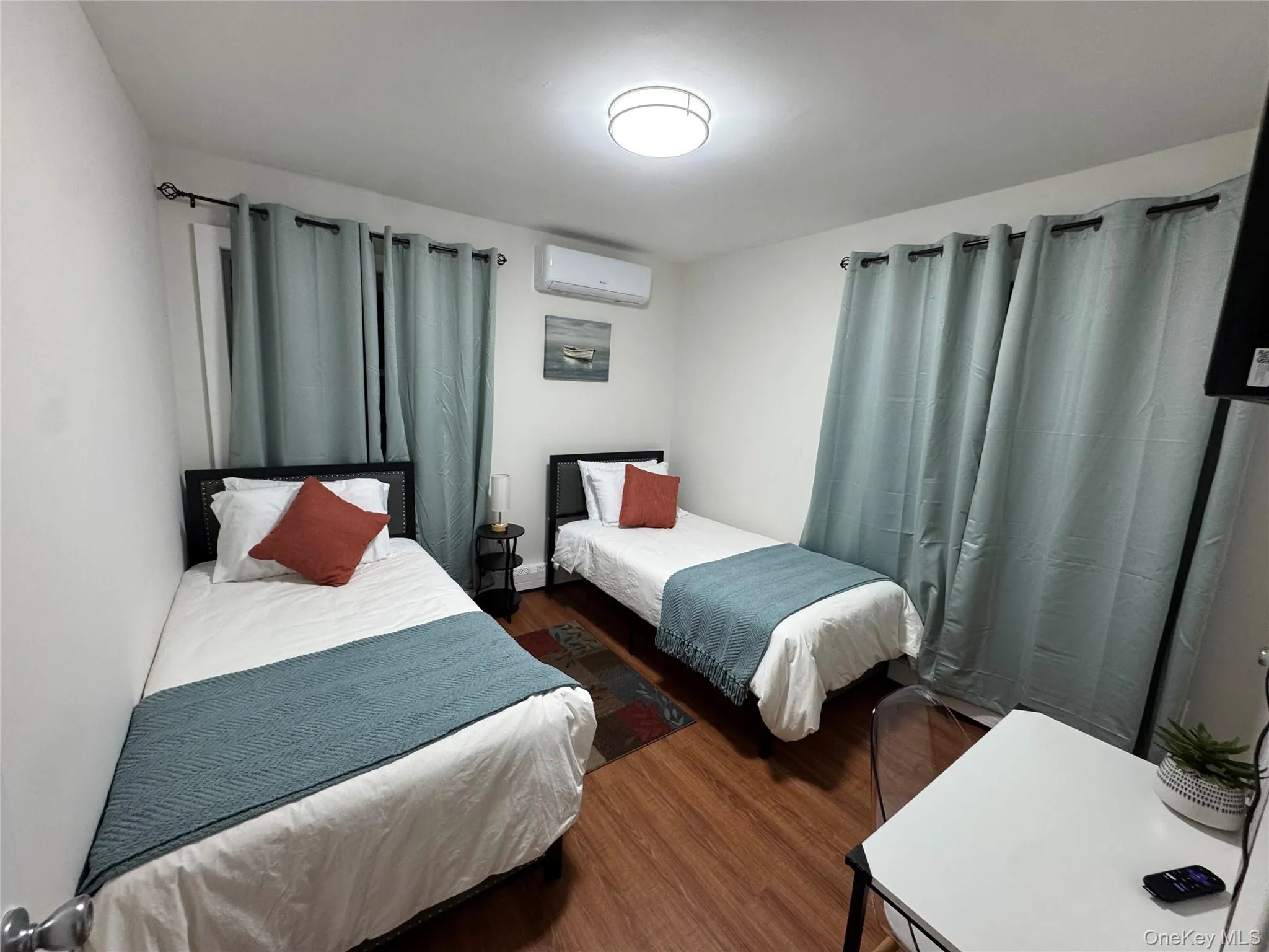 Bedroom with dark wood-style floors and a wall mounted air conditioner Bedroom with dark wood-style floors and a wall mounted air conditioner
