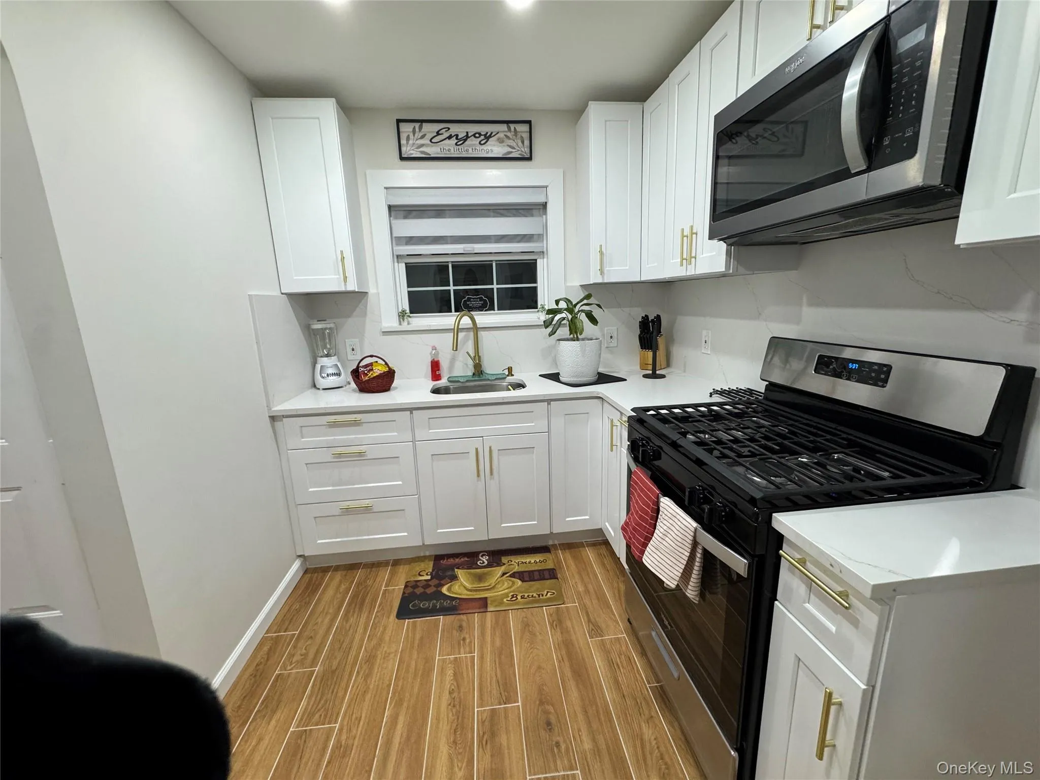 Kitchen featuring appliances with stainless steel finishes, wood tiled floors, white cabinetry, and backsplash Kitchen featuring appliances with stainless steel finishes, wood tiled floors, white cabinetry, and backsplash
