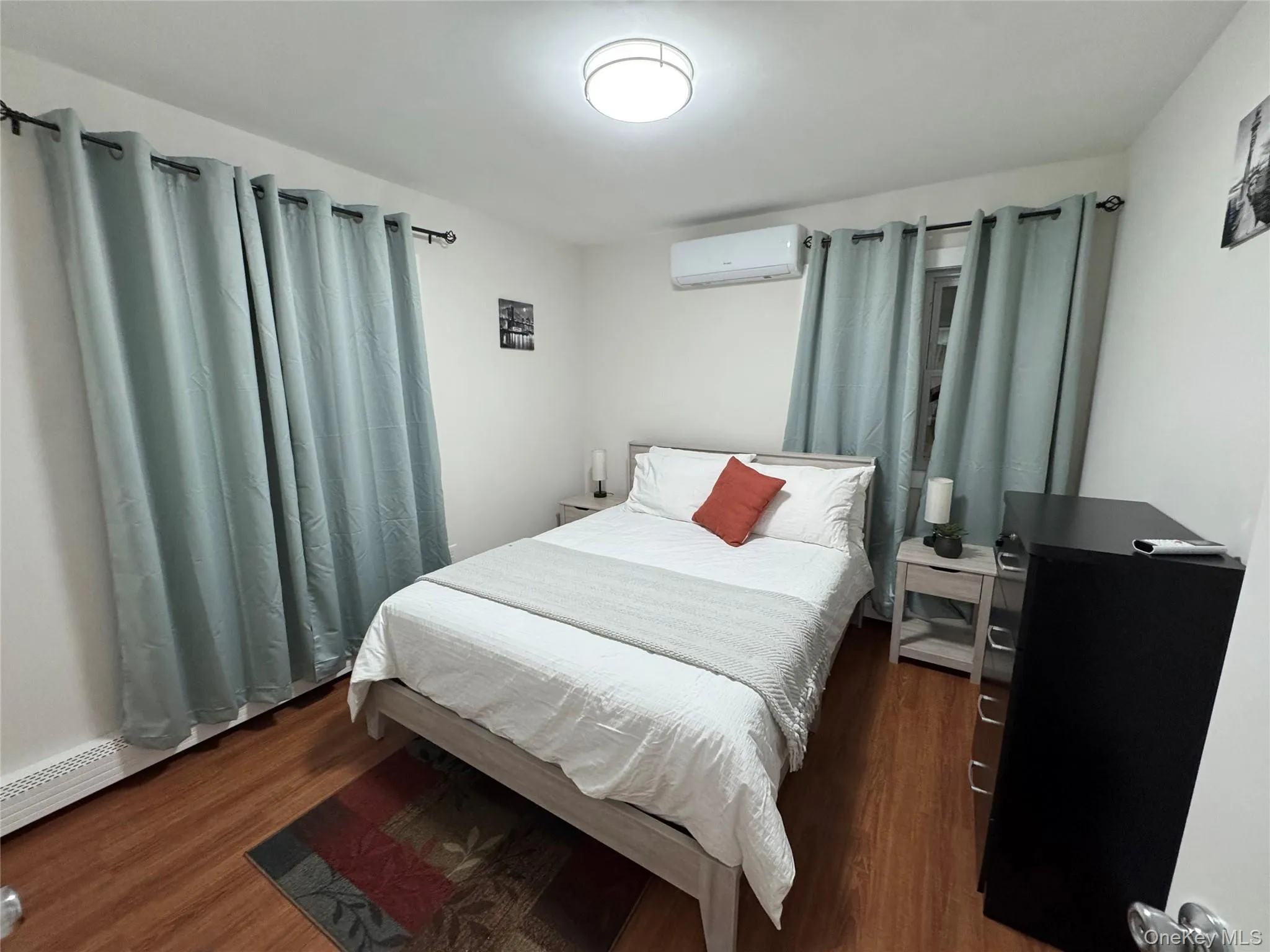 Bedroom with wood finished floors and a wall mounted AC Bedroom with wood finished floors and a wall mounted AC