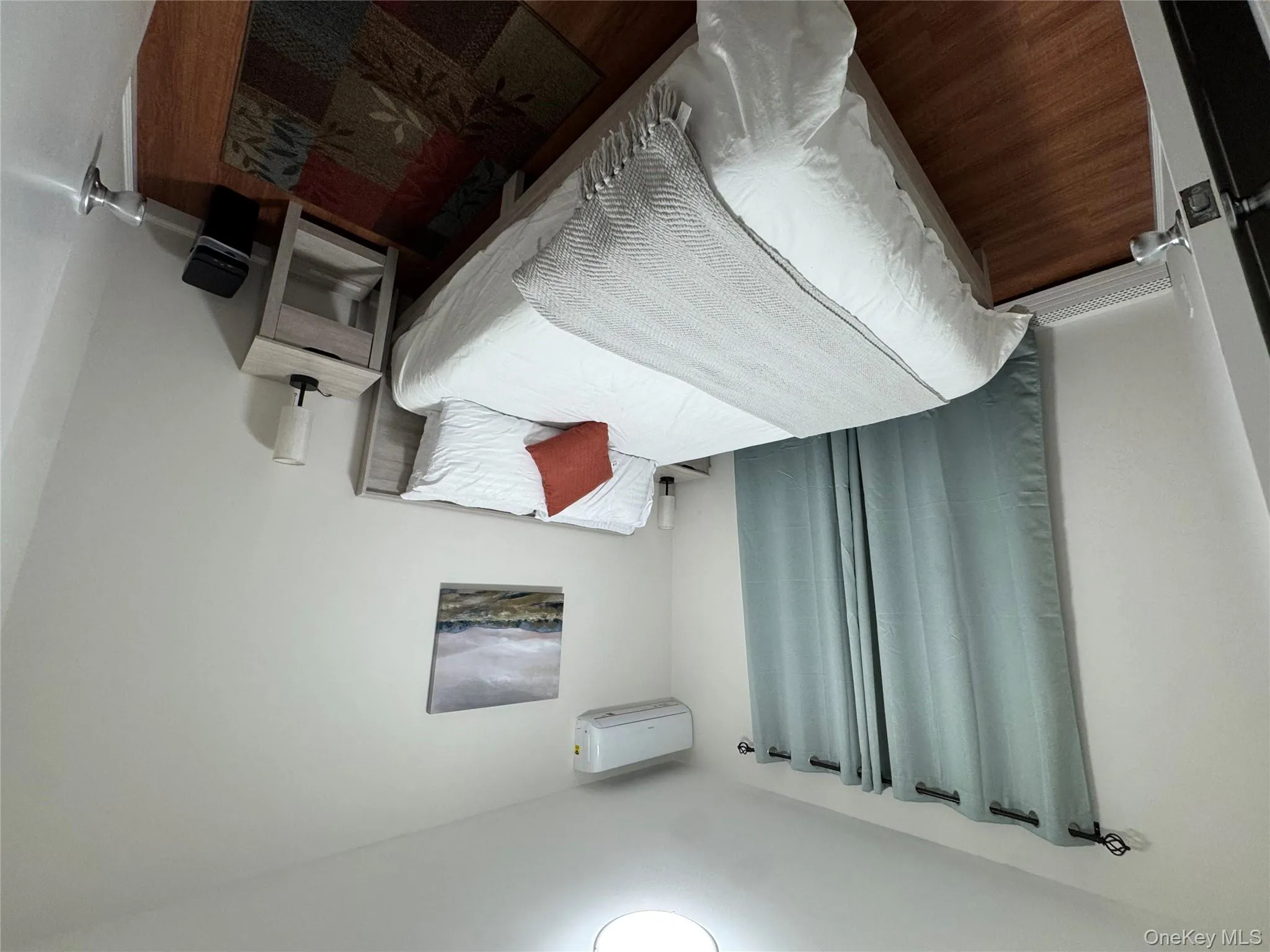 Bedroom featuring wood finished floors and a wall mounted air conditioner Bedroom featuring wood finished floors and a wall mounted air conditioner