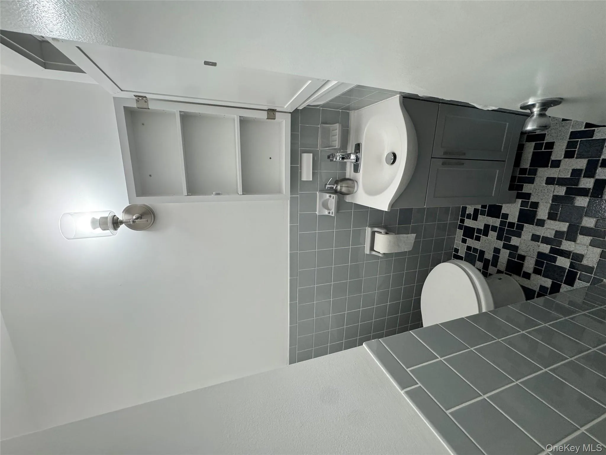 Half bathroom with tile walls, wainscoting, vanity, and dark tile patterned floors Half bathroom with tile walls, wainscoting, vanity, and dark tile patterned floors