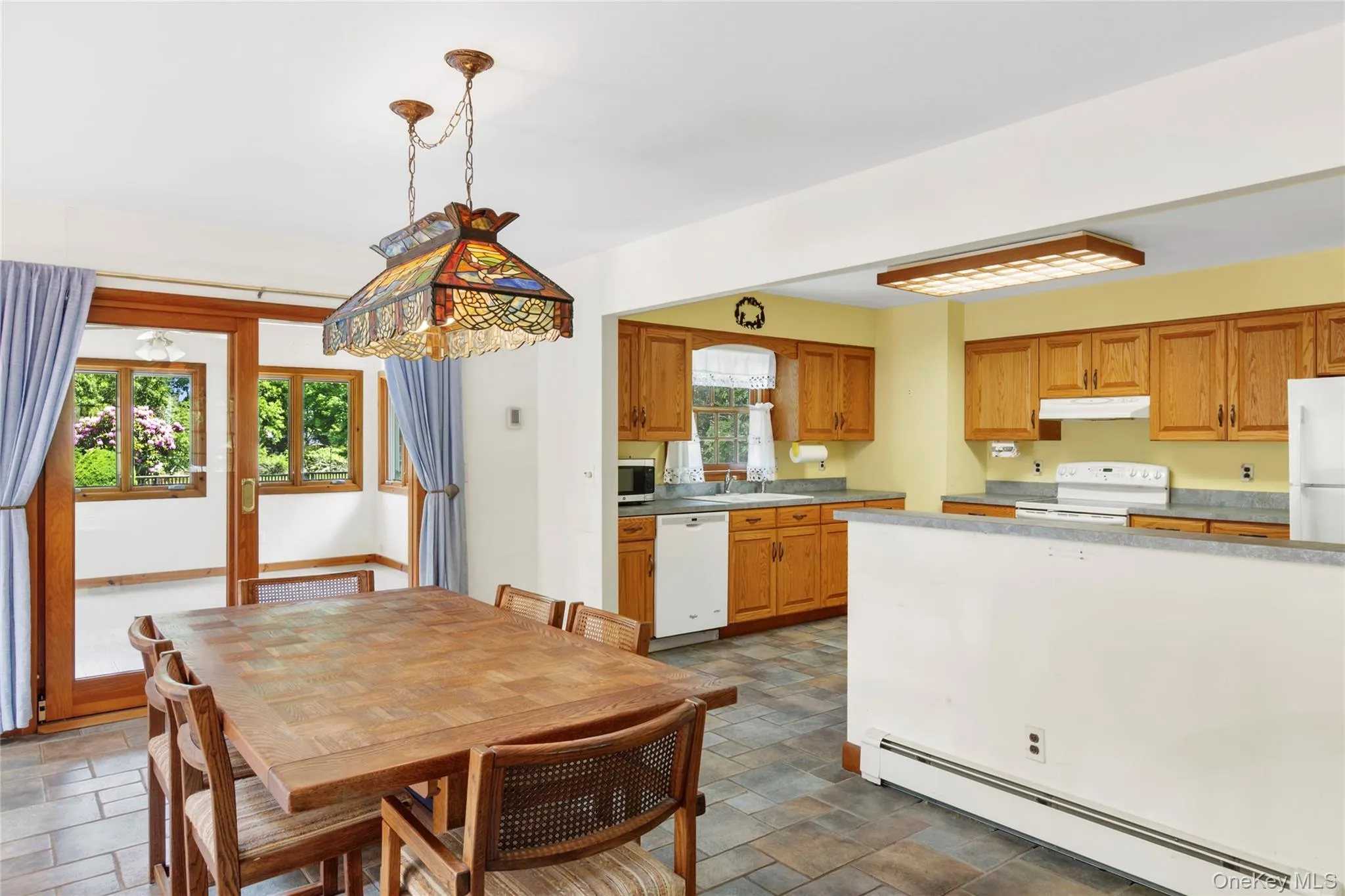 Open-concept dining area with sliding glass doors leading out to the sun room. Open-concept dining area with sliding glass doors leading out to the sun room.