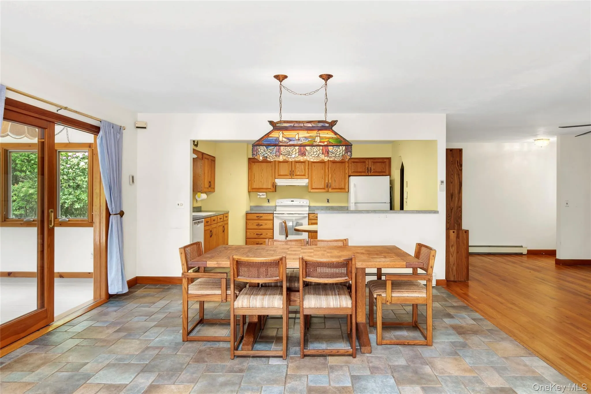 Open-concept dining area with sliding glass doors leading out to the sun room. Open-concept dining area with sliding glass doors leading out to the sun room.