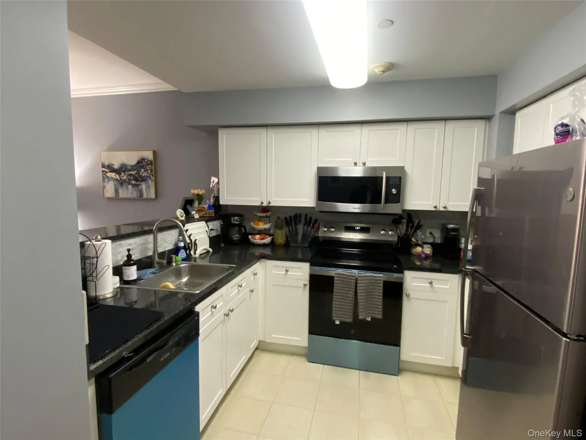 Kitchen with appliances with stainless steel finishes, white cabinets, and light tile patterned floors Kitchen with appliances with stainless steel finishes, white cabinets, and light tile patterned floors