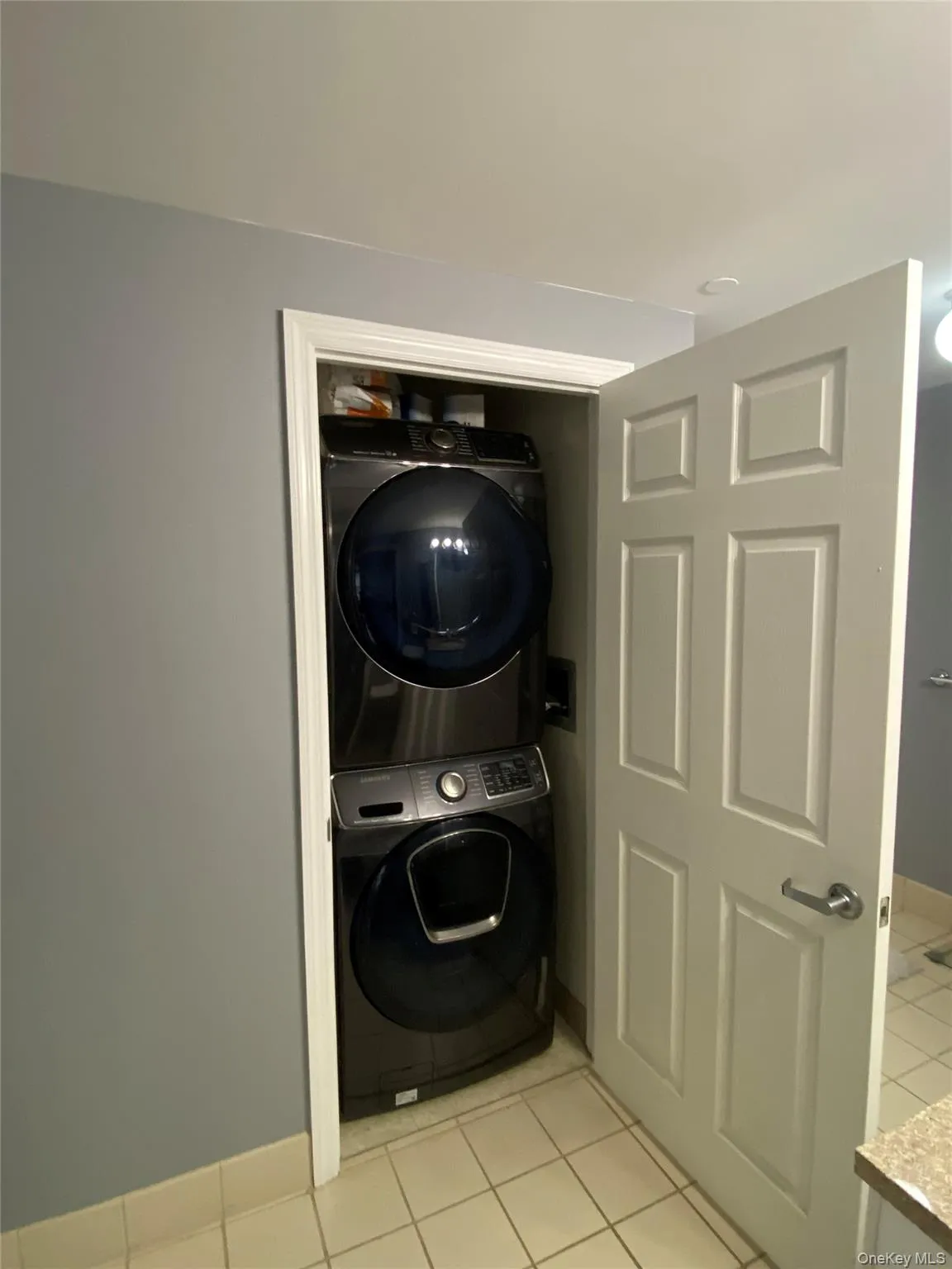 Laundry room with light tile patterned floors and stacked washer / dryer Laundry room with light tile patterned floors and stacked washer / dryer