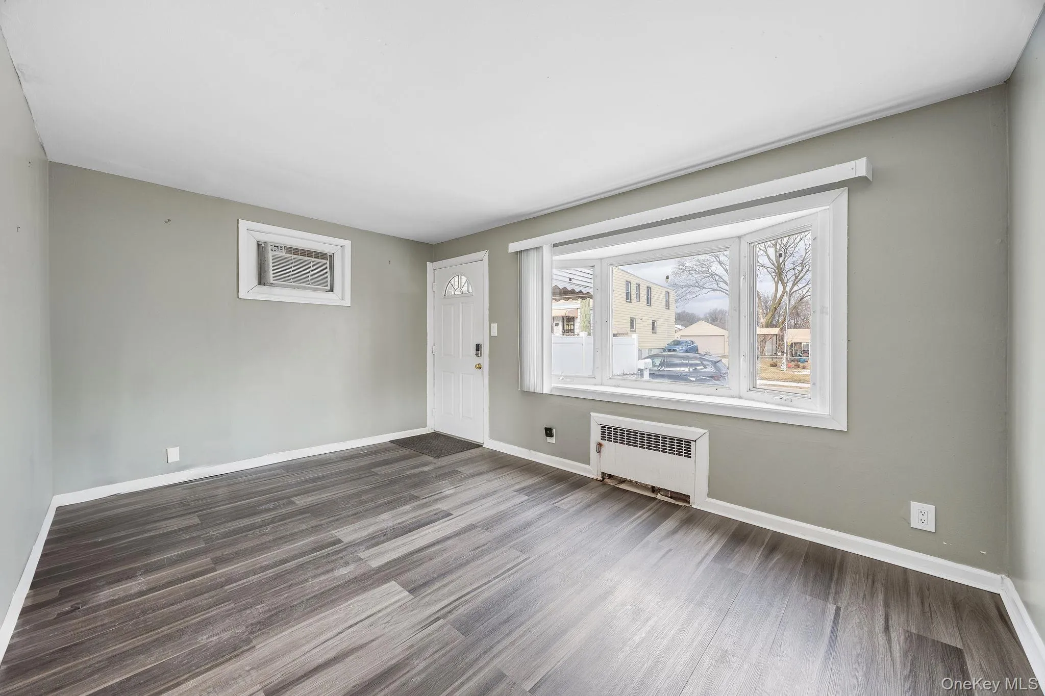 Unfurnished room featuring radiator heating unit and dark wood-style flooring Unfurnished room featuring radiator heating unit and dark wood-style flooring