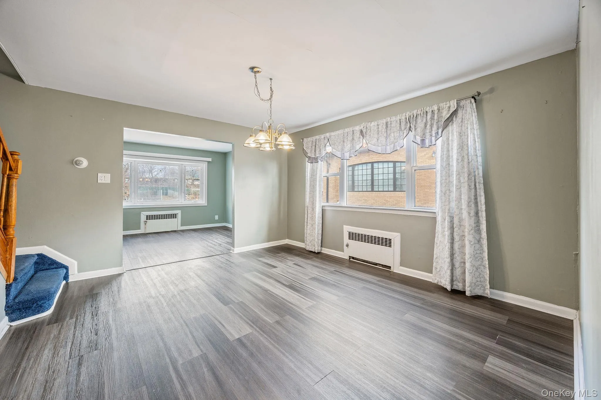Unfurnished dining area with a chandelier, radiator heating unit, and wood finished floors Unfurnished dining area with a chandelier, radiator heating unit, and wood finished floors