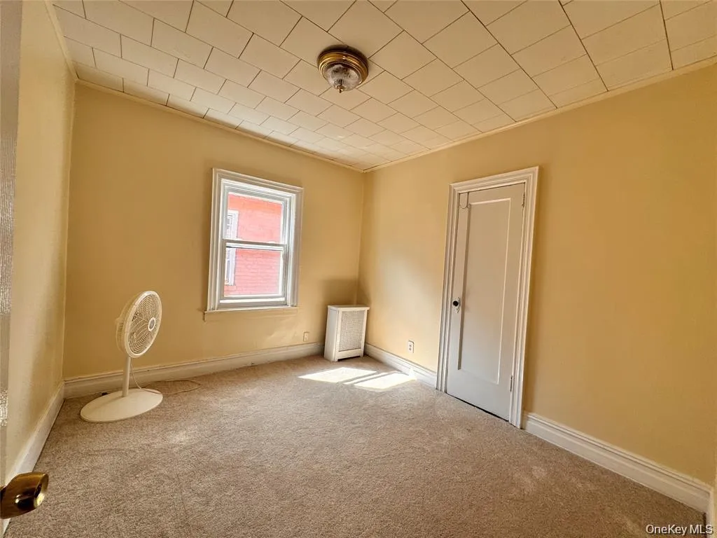 Carpeted spare room featuring baseboards and radiator heating unit Carpeted spare room featuring baseboards and radiator heating unit