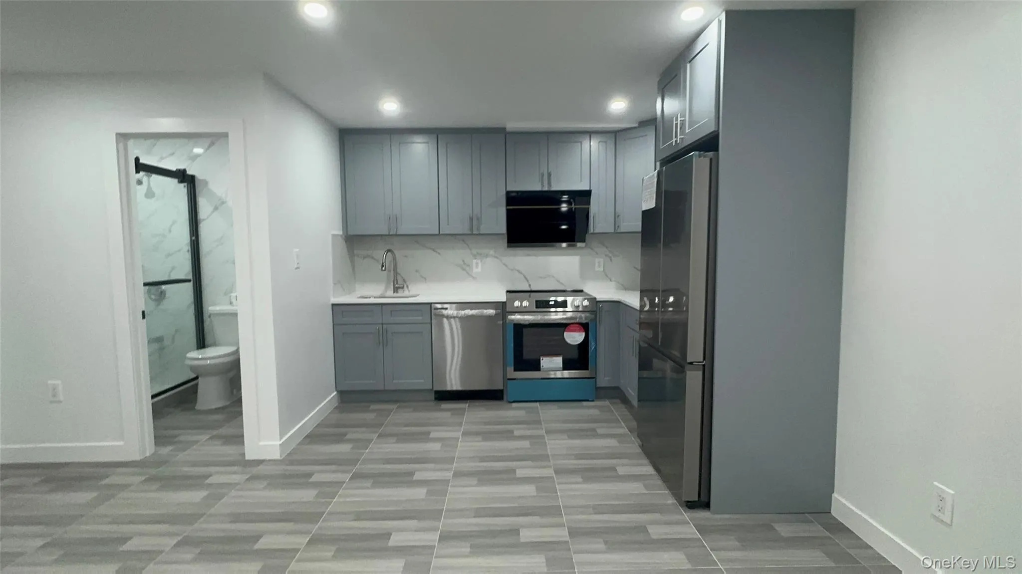 Kitchen featuring gray cabinets, stainless steel appliances, recessed lighting, light stone countertops, and tasteful backsplash Kitchen featuring gray cabinets, stainless steel appliances, recessed lighting, light stone countertops, and tasteful backsplash