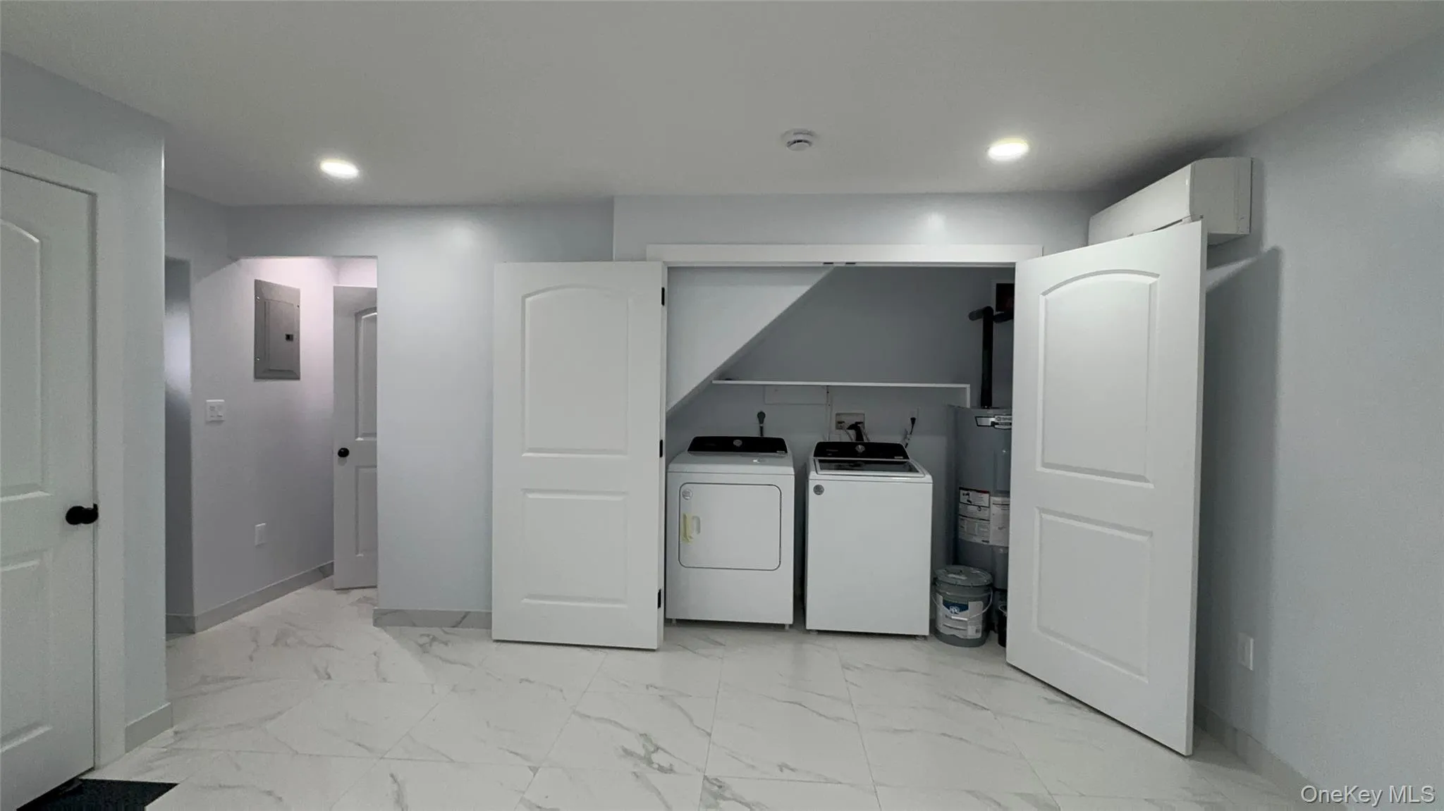 Washroom with light marble finish floors, washing machine and clothes dryer, water heater, electric panel, and recessed lighting Washroom with light marble finish floors, washing machine and clothes dryer, water heater, electric panel, and recessed lighting