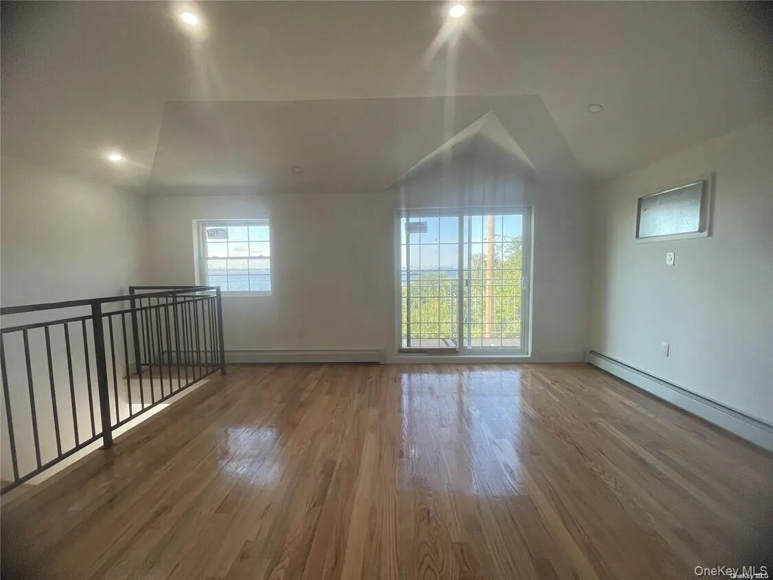 Additional living space with wood finished floors, vaulted ceiling, baseboard heating, and a baseboard heating unit Additional living space with wood finished floors, vaulted ceiling, baseboard heating, and a baseboard heating unit