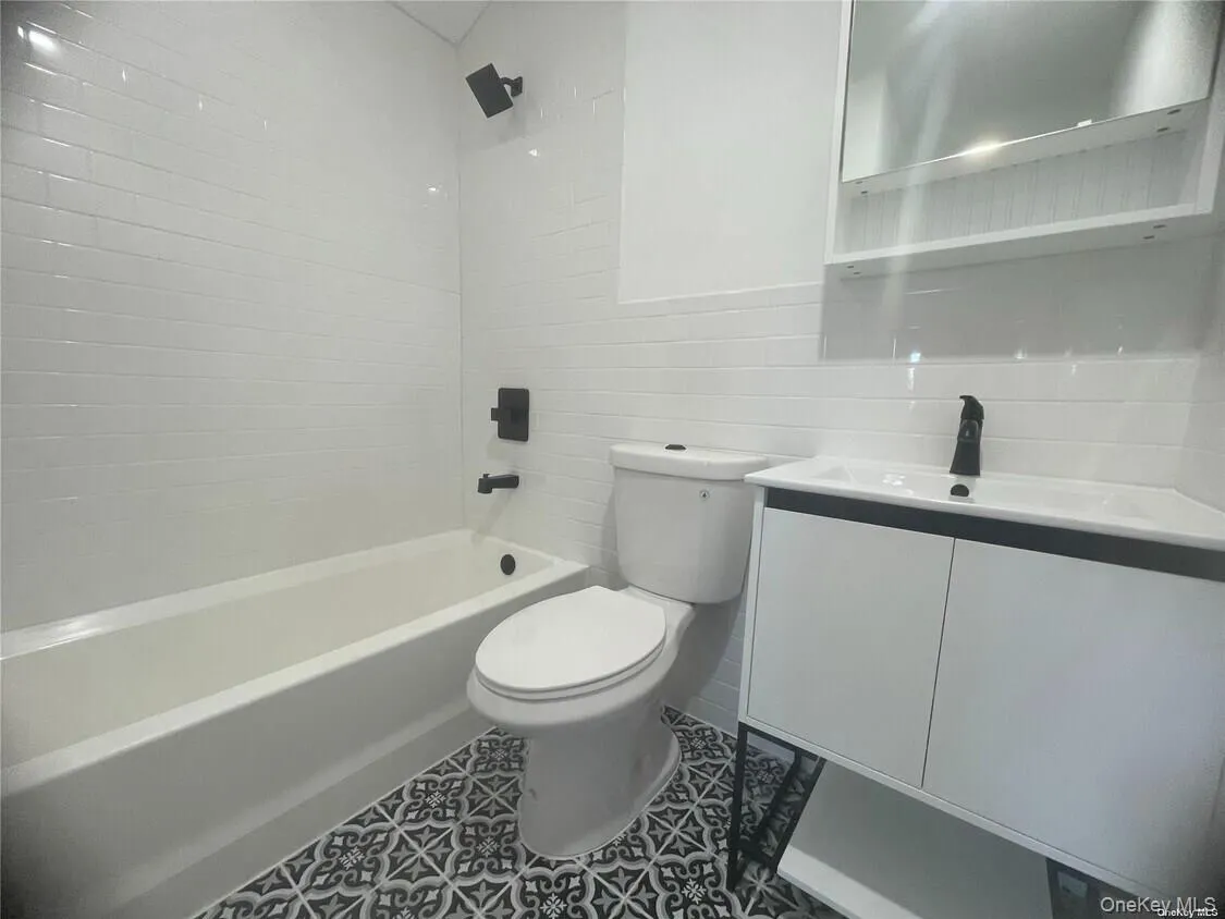 Full bathroom with vanity, tile walls, tub / shower combination, dark tile patterned flooring, and backsplash Full bathroom with vanity, tile walls, tub / shower combination, dark tile patterned flooring, and backsplash