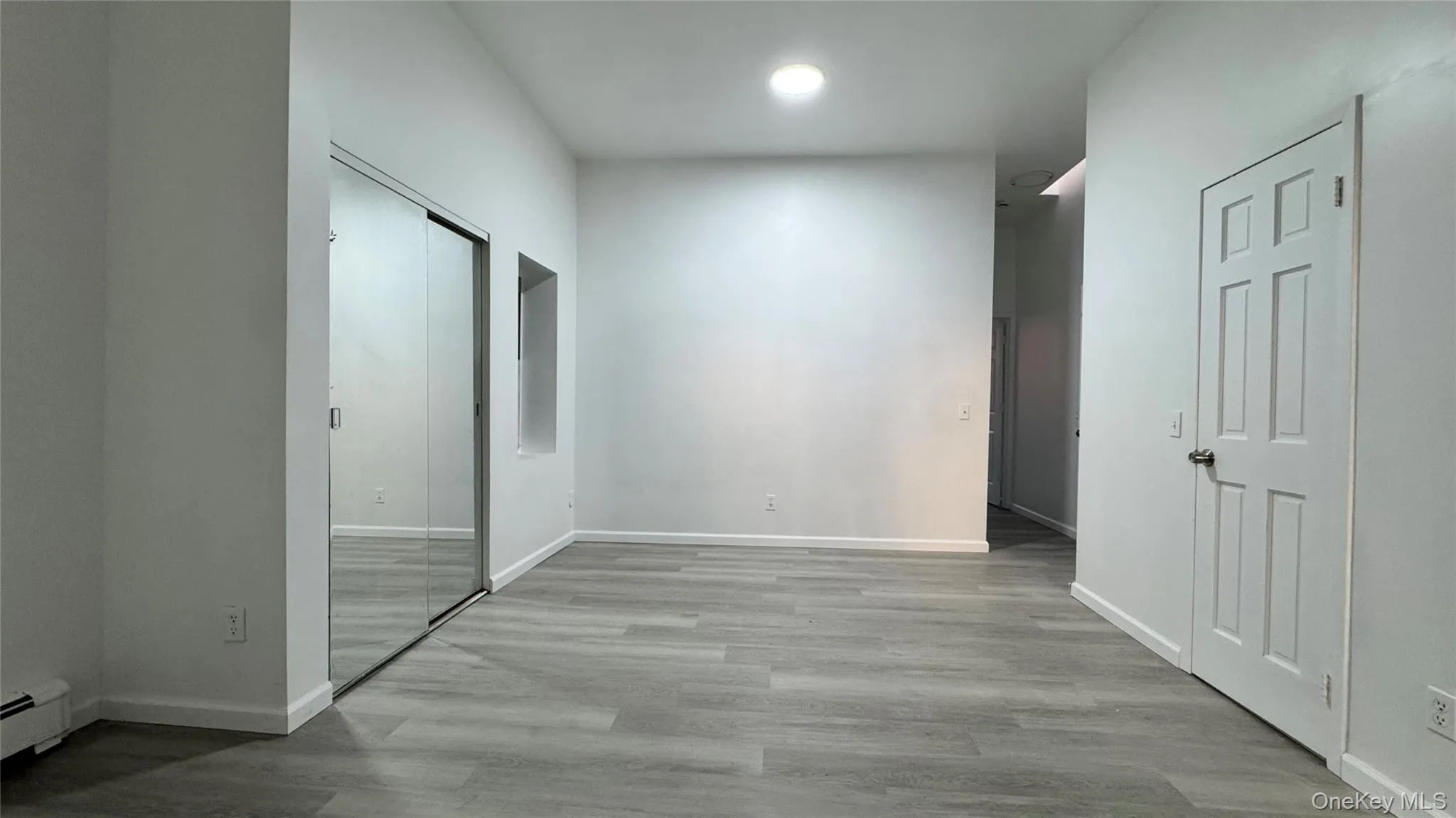 Hall with light wood-style flooring, baseboard heating, and recessed lighting Hall with light wood-style flooring, baseboard heating, and recessed lighting