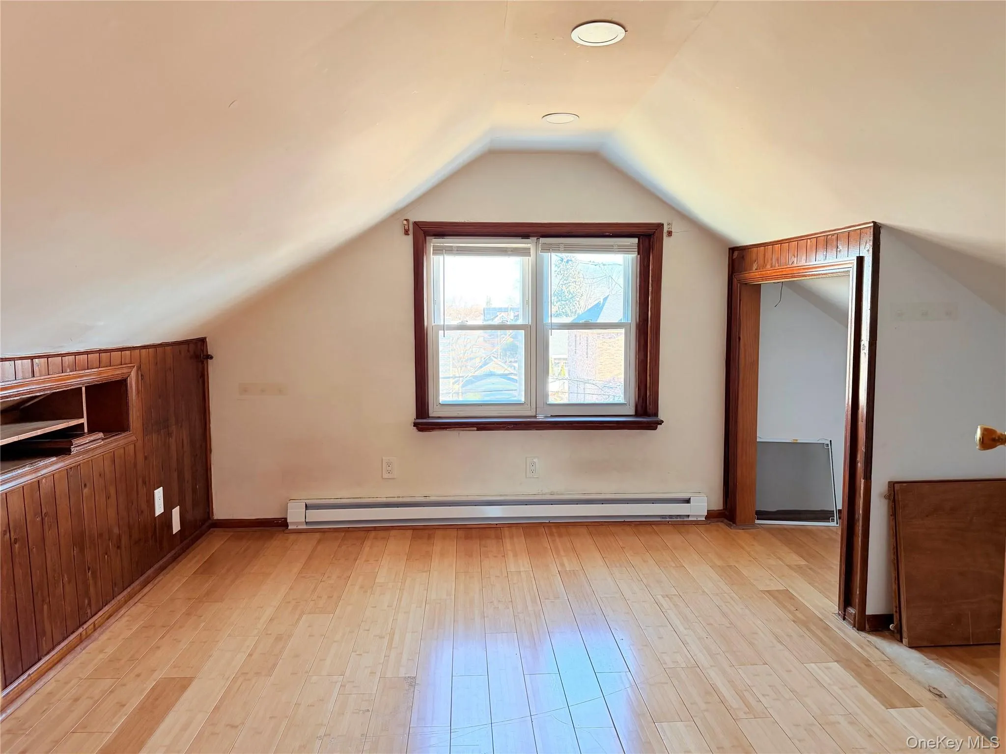 Additional living space with light wood-style floors, a baseboard radiator, and vaulted ceiling Additional living space with light wood-style floors, a baseboard radiator, and vaulted ceiling