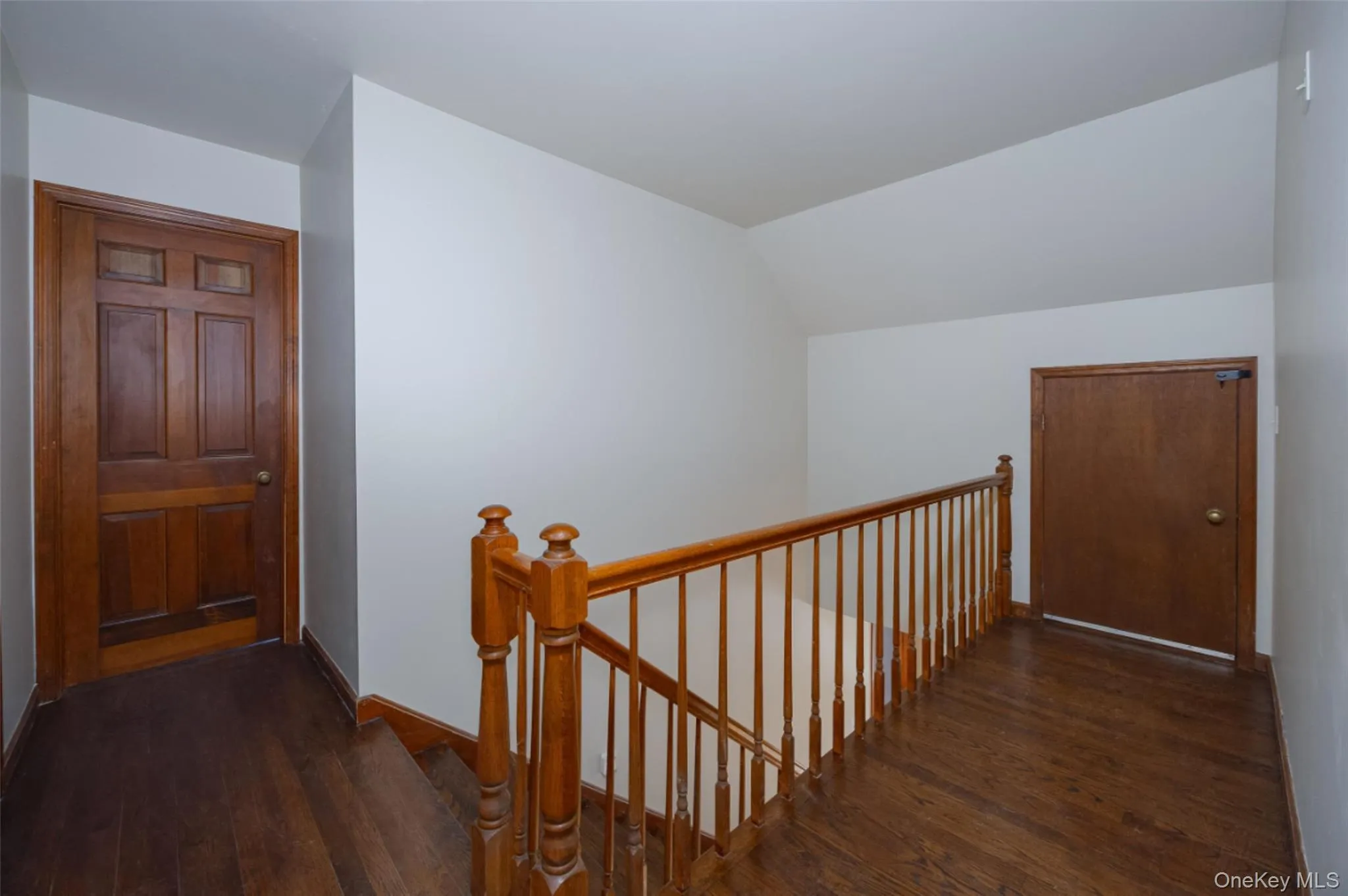 Hall with an upstairs landing, lofted ceiling, and storage closet Hall with an upstairs landing, lofted ceiling, and storage closet