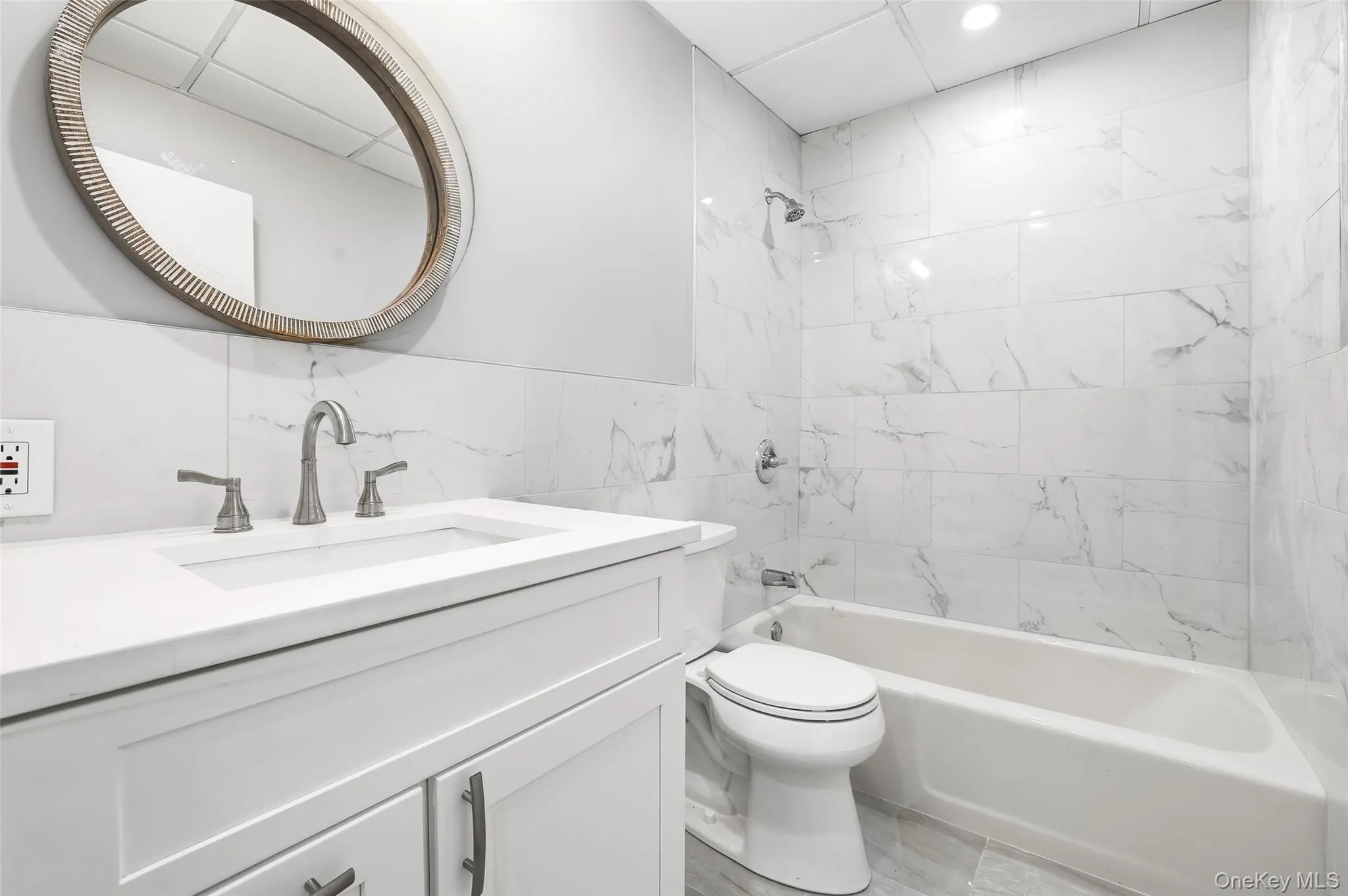 Bathroom featuring bathing tub / shower combination, vanity, and tile walls Bathroom featuring bathing tub / shower combination, vanity, and tile walls