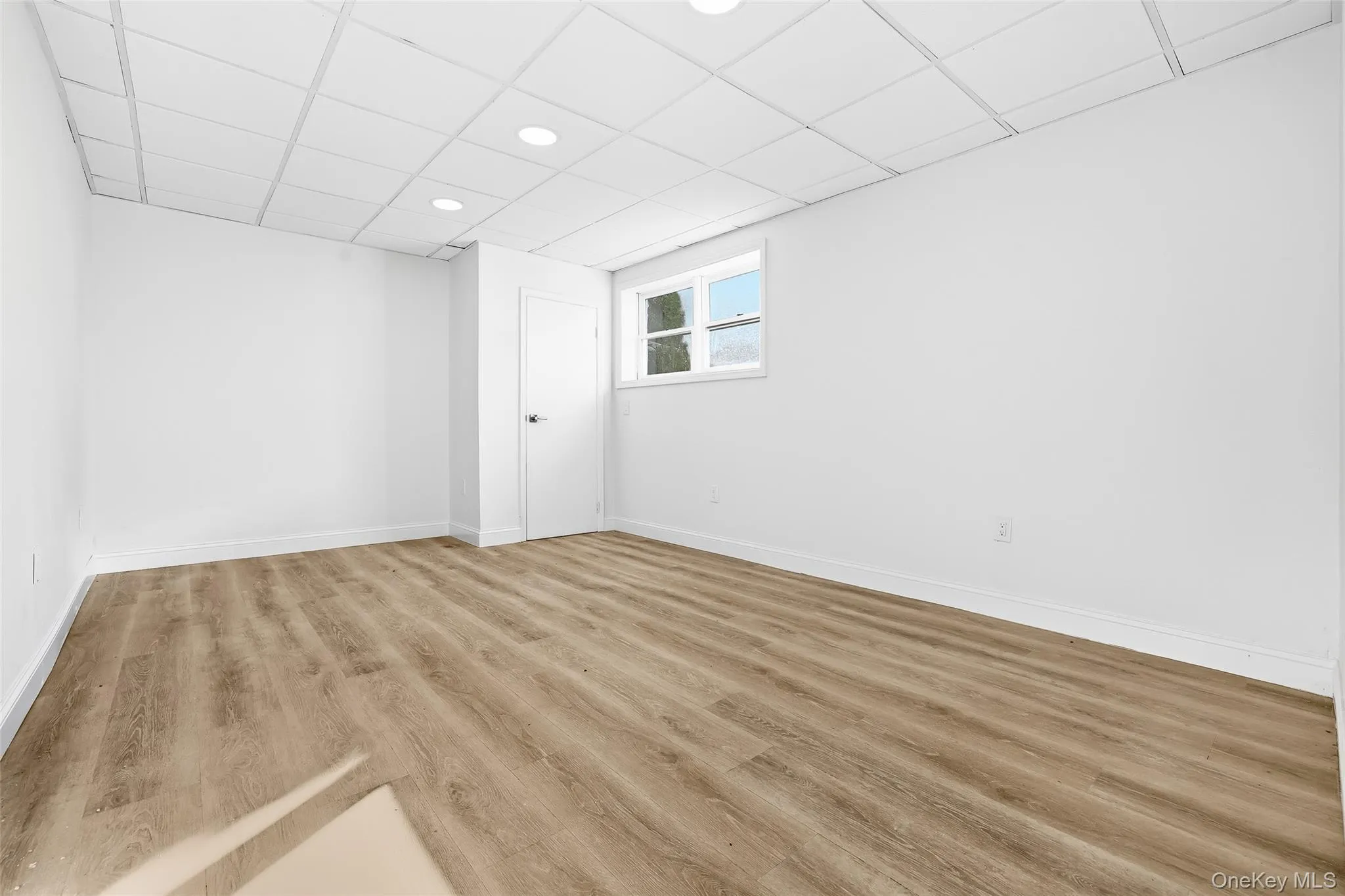 Basement featuring a paneled ceiling, wood finished floors, and recessed lighting Basement featuring a paneled ceiling, wood finished floors, and recessed lighting