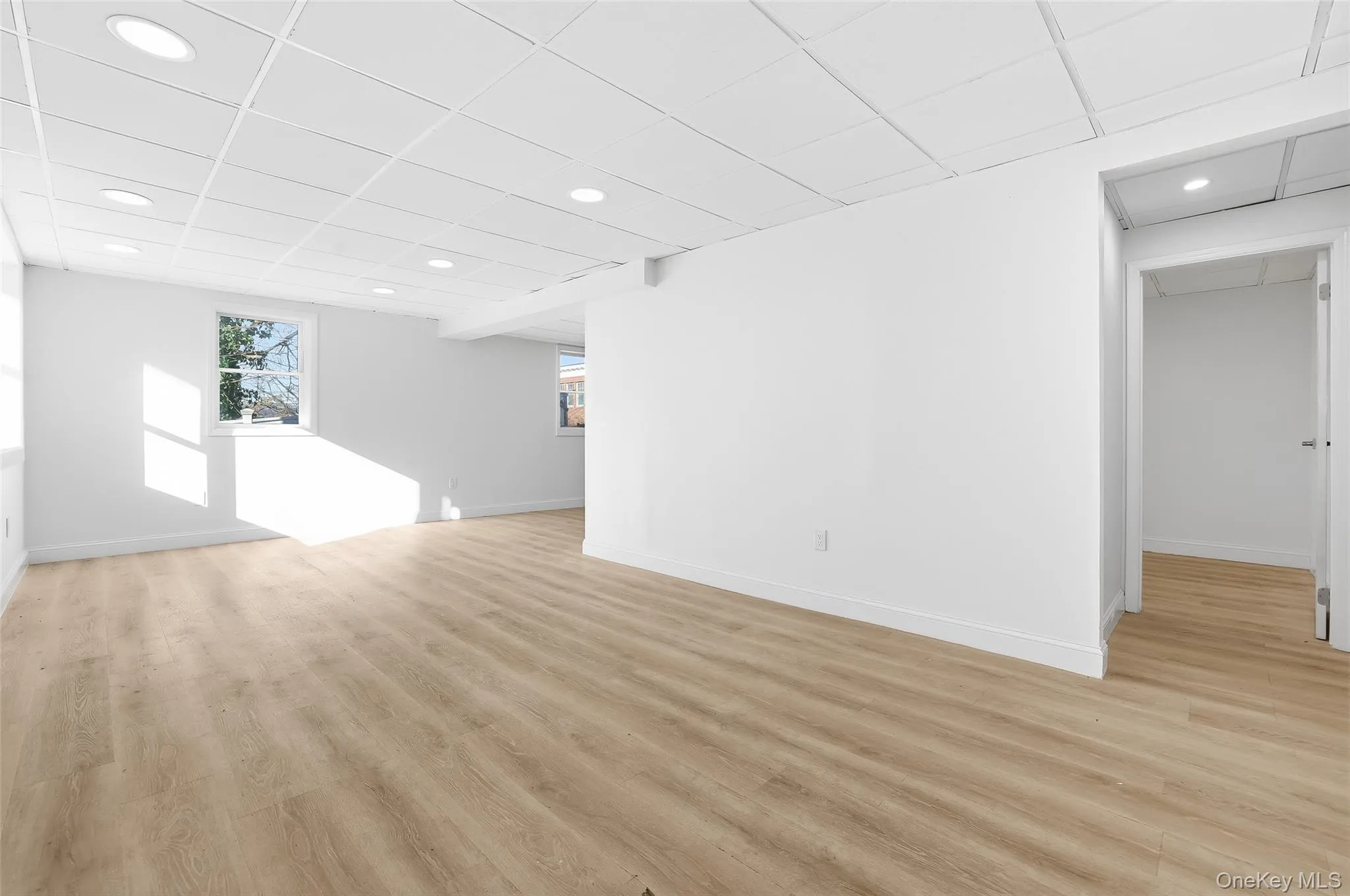 Empty room featuring a drop ceiling, light wood-style flooring, and recessed lighting Empty room featuring a drop ceiling, light wood-style flooring, and recessed lighting