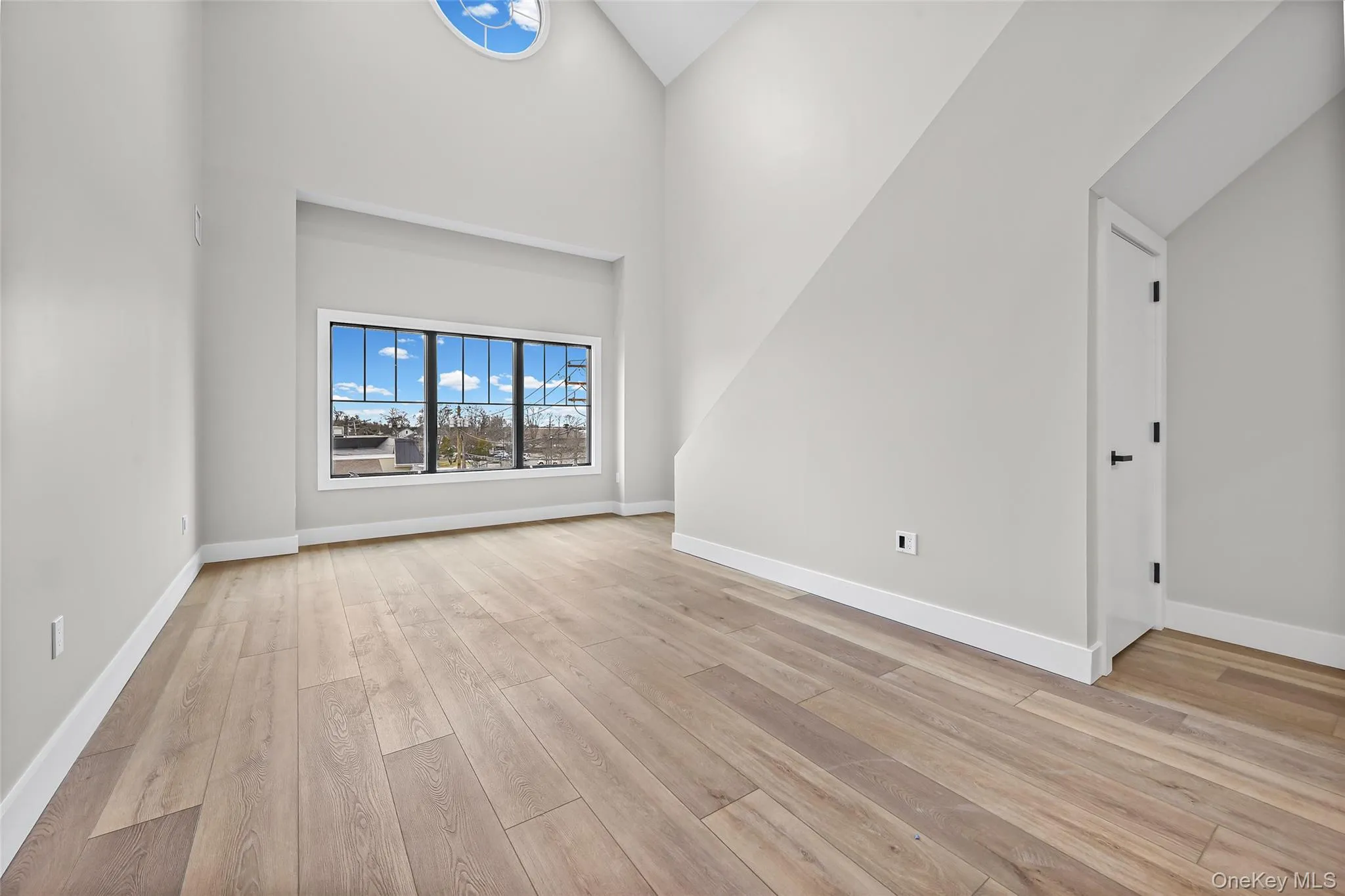 Unfurnished living room featuring high vaulted ceiling and light wood-style floors Unfurnished living room featuring high vaulted ceiling and light wood-style floors