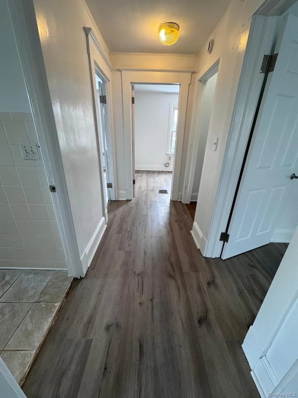 Corridor featuring dark wood-type flooring and baseboards Corridor featuring dark wood-type flooring and baseboards