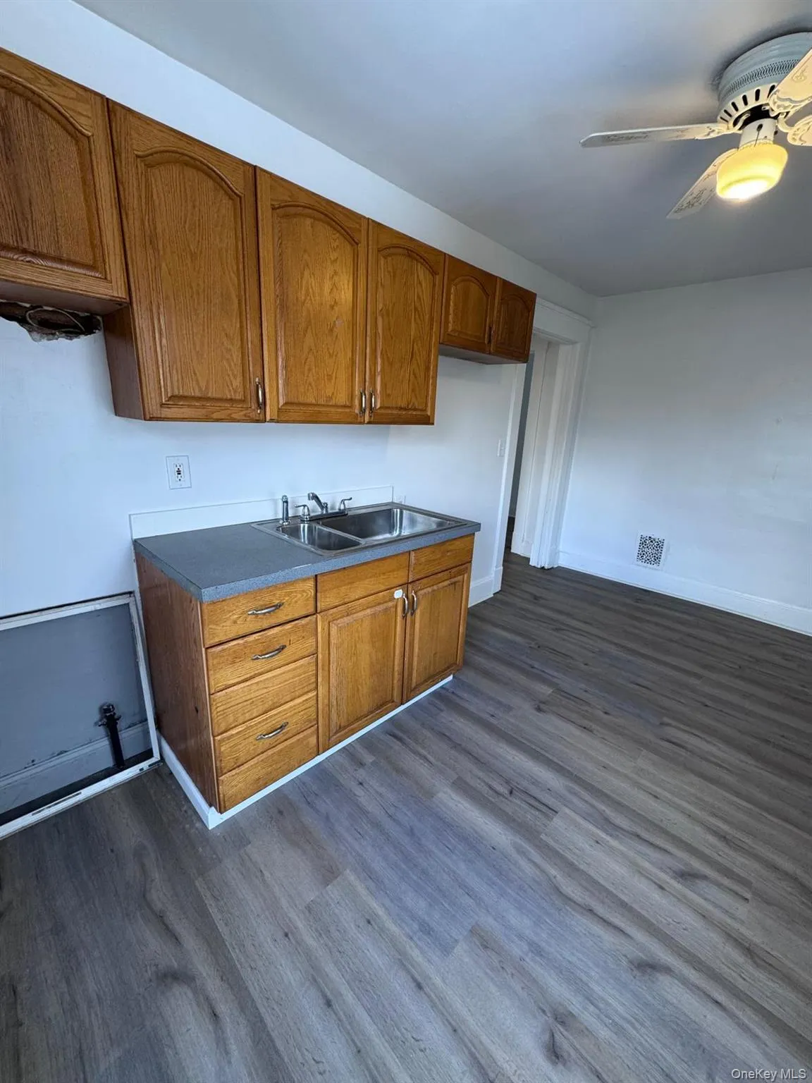 Kitchen featuring brown cabinetry, dark countertops, a ceiling fan, and dark wood finished floors Kitchen featuring brown cabinetry, dark countertops, a ceiling fan, and dark wood finished floors