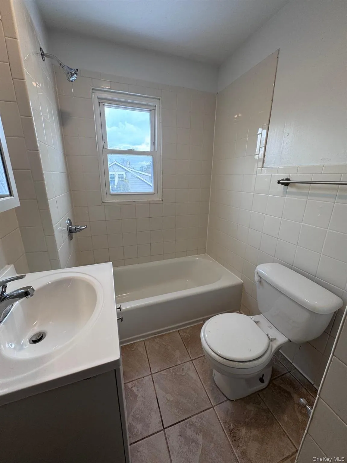 Bathroom with tile walls, vanity, bathtub / shower combination, and light tile patterned flooring Bathroom with tile walls, vanity, bathtub / shower combination, and light tile patterned flooring