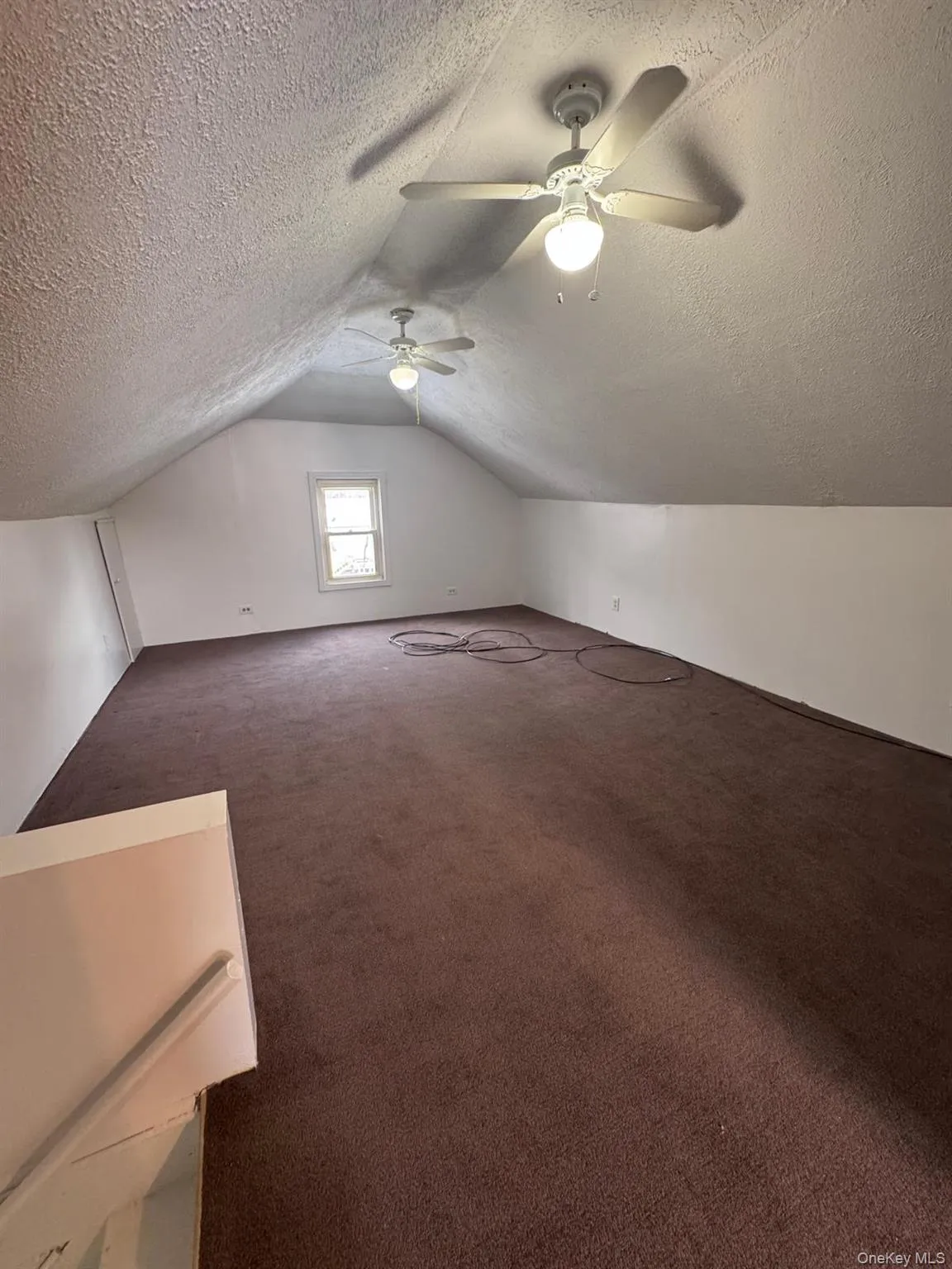 Bonus room with lofted ceiling, dark colored carpet, a textured ceiling, and a ceiling fan Bonus room with lofted ceiling, dark colored carpet, a textured ceiling, and a ceiling fan