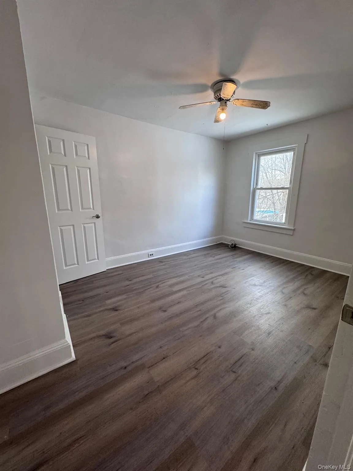 Unfurnished room with dark wood-type flooring and ceiling fan Unfurnished room with dark wood-type flooring and ceiling fan