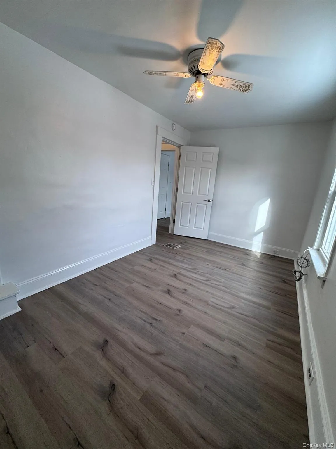 Unfurnished bedroom featuring dark wood-style floors and a ceiling fan Unfurnished bedroom featuring dark wood-style floors and a ceiling fan