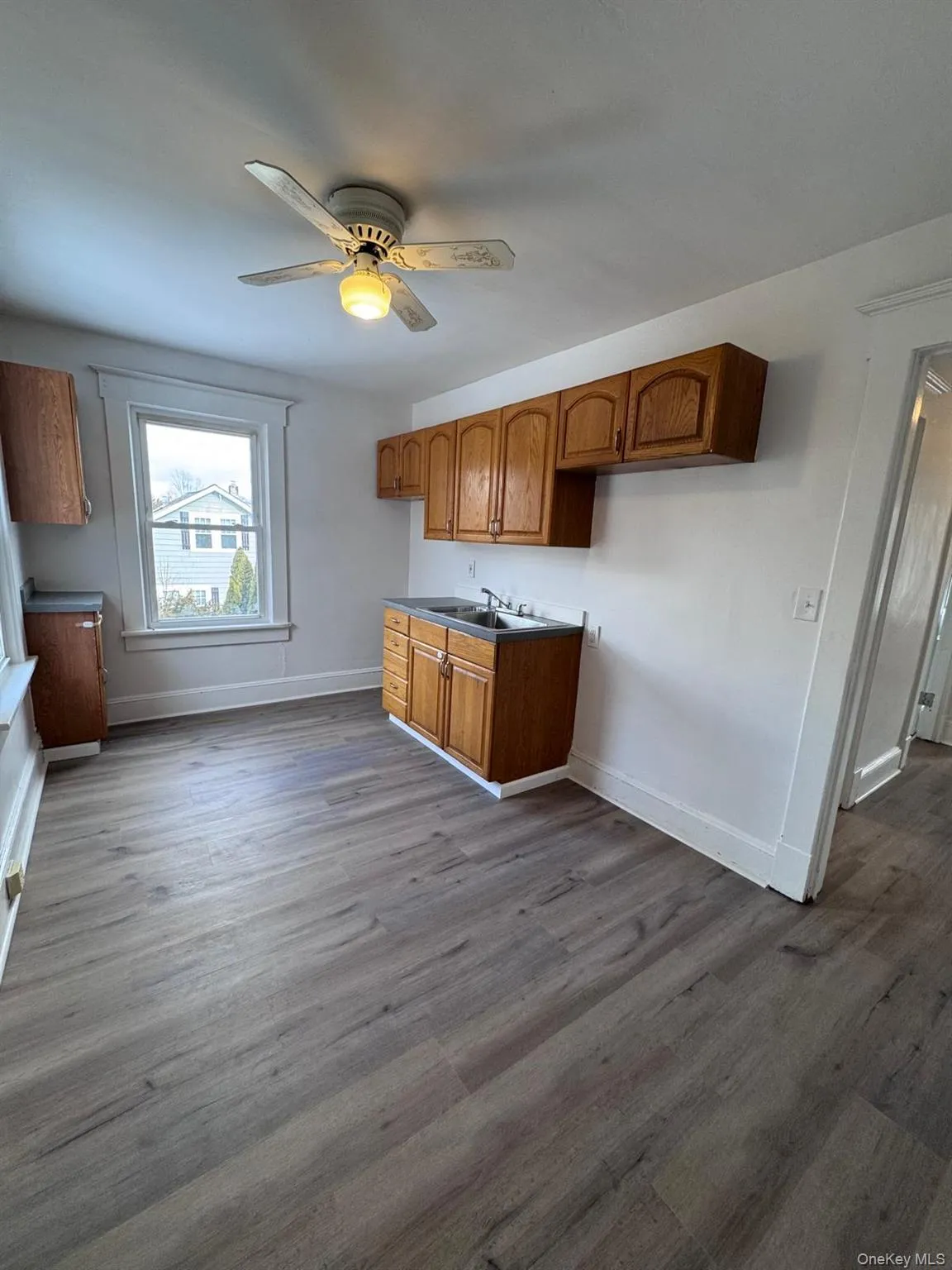 Kitchen with brown cabinets, a ceiling fan, and dark wood finished floors Kitchen with brown cabinets, a ceiling fan, and dark wood finished floors