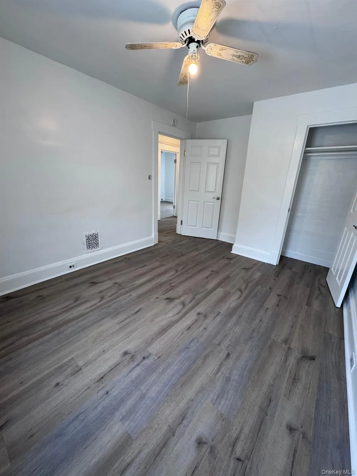 Unfurnished bedroom featuring dark wood finished floors, a ceiling fan, and a closet Unfurnished bedroom featuring dark wood finished floors, a ceiling fan, and a closet