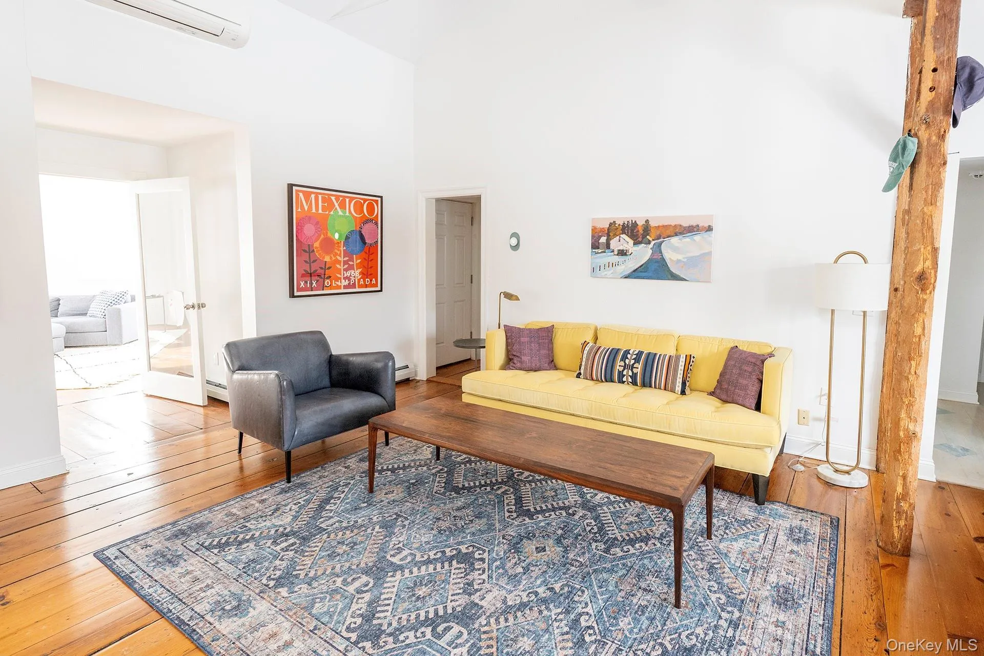 Living room featuring hardwood / wood-style flooring, a wall unit AC, and high vaulted ceiling Living room featuring hardwood / wood-style flooring, a wall unit AC, and high vaulted ceiling