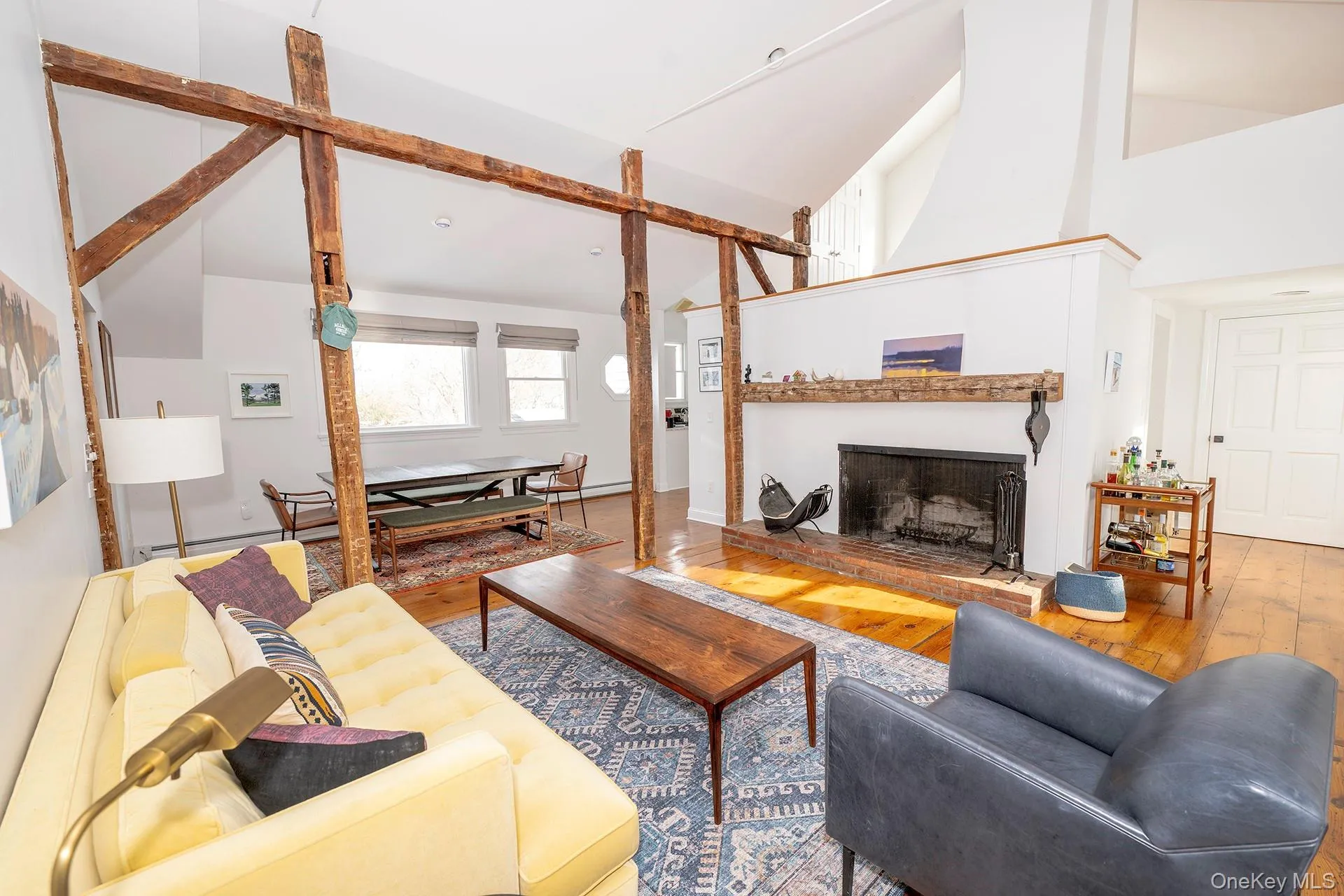 Living area featuring a brick fireplace, wood-type flooring, and high vaulted ceiling Living area featuring a brick fireplace, wood-type flooring, and high vaulted ceiling