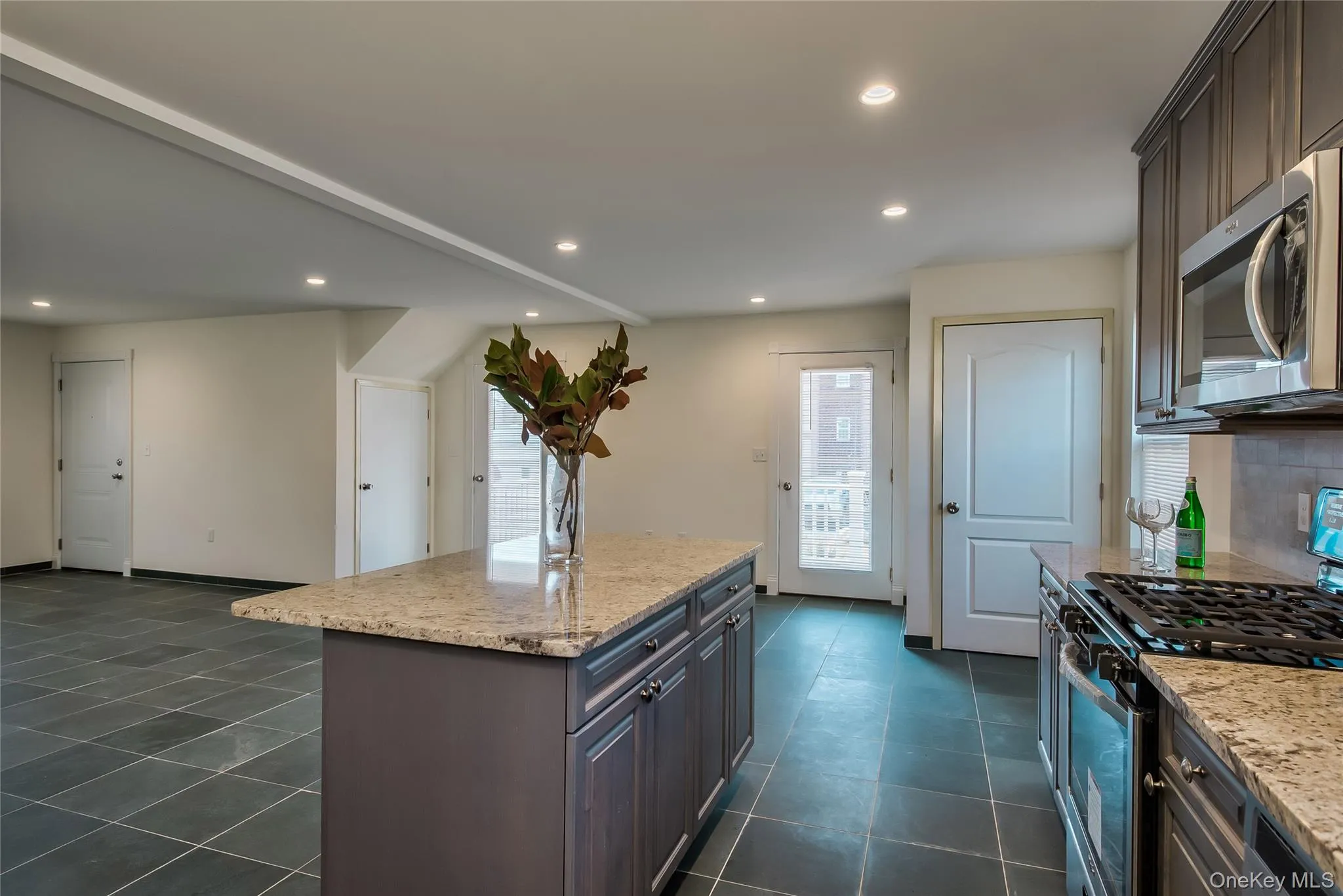 Kitchen with gas range, light stone counters, stainless steel microwave, recessed lighting, and a center island Kitchen with gas range, light stone counters, stainless steel microwave, recessed lighting, and a center island
