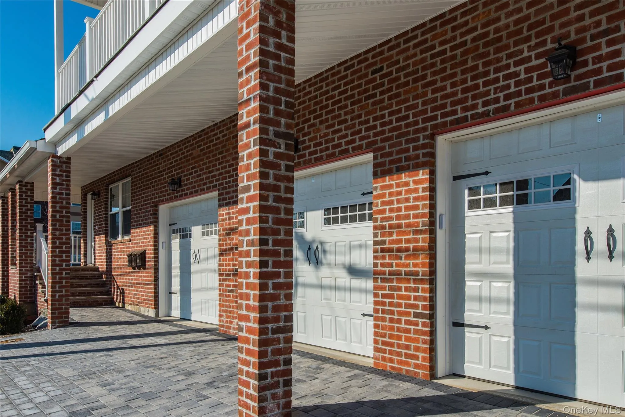 Entrance to property with brick siding, decorative driveway, a patio, and a garage Entrance to property with brick siding, decorative driveway, a patio, and a garage