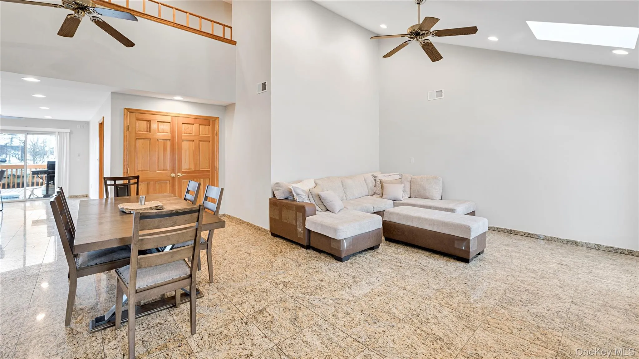 Living room featuring a ceiling fan, granite floors, recessed lighting, a skylight, and high vaulted ceiling Living room featuring a ceiling fan, granite floors, recessed lighting, a skylight, and high vaulted ceiling