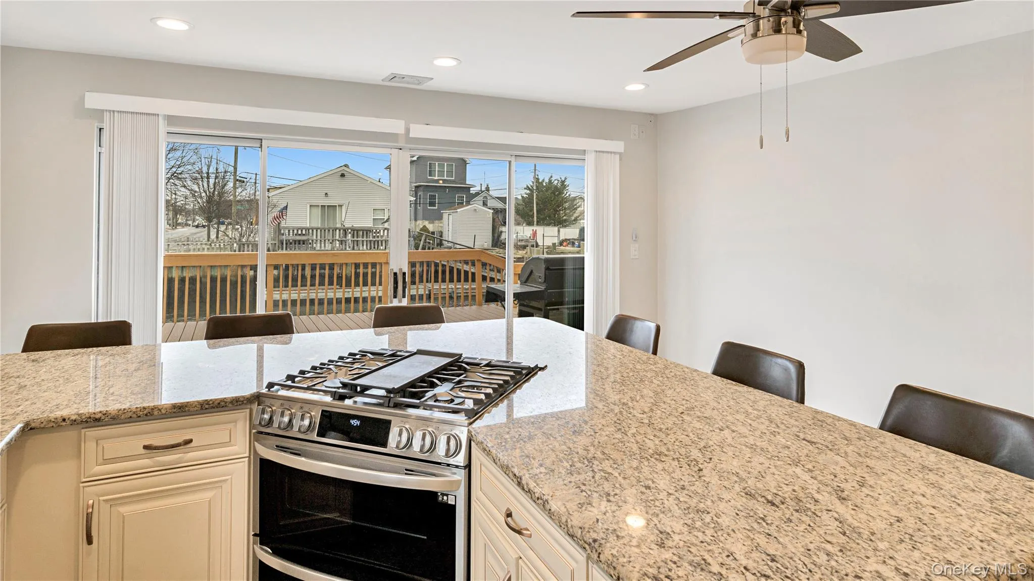 Kitchen featuring a breakfast bar area, light stone countertops, range with two ovens, recessed lighting, and ceiling fan Kitchen featuring a breakfast bar area, light stone countertops, range with two ovens, recessed lighting, and ceiling fan