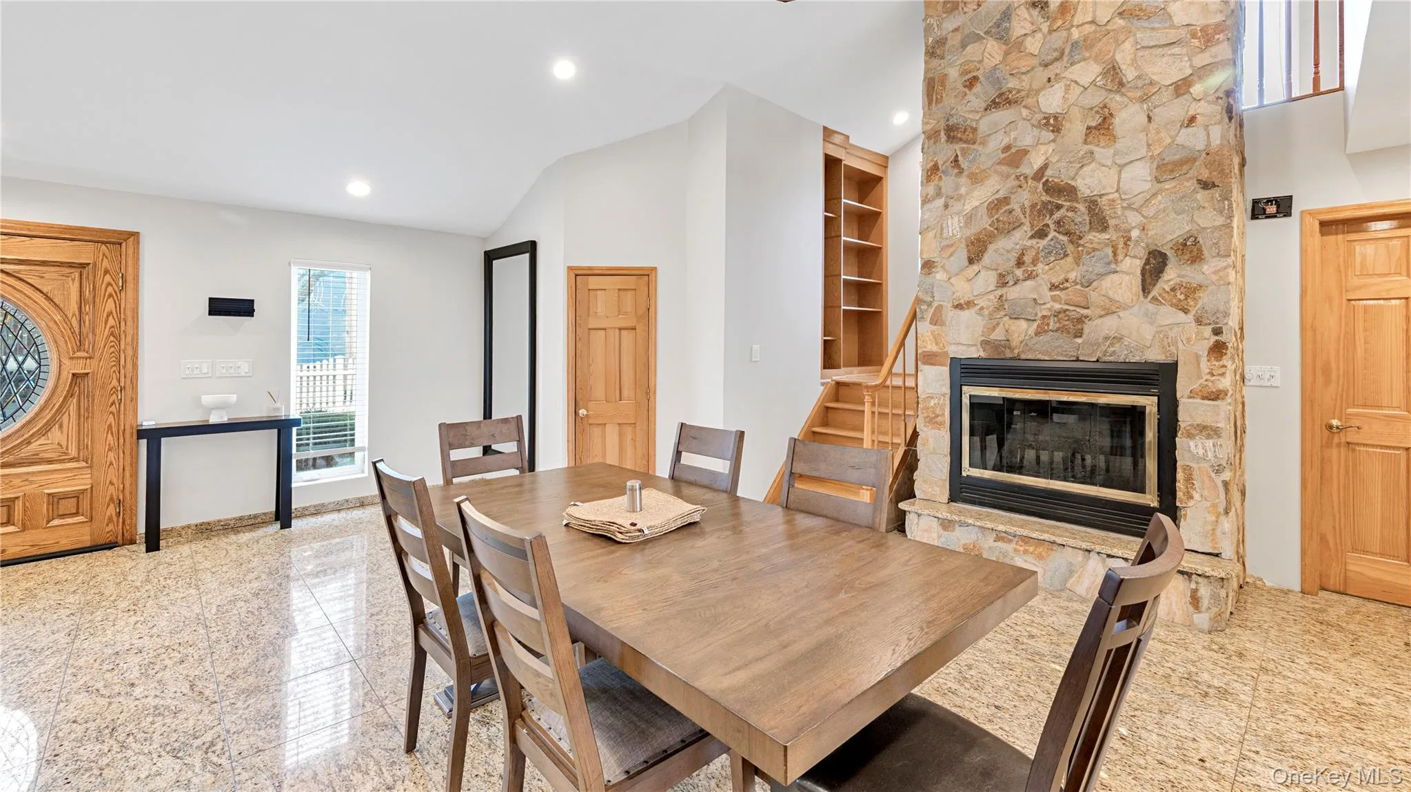 Dining room with granite floors, a stone fireplace, vaulted ceiling, recessed lighting, and built in features Dining room with granite floors, a stone fireplace, vaulted ceiling, recessed lighting, and built in features