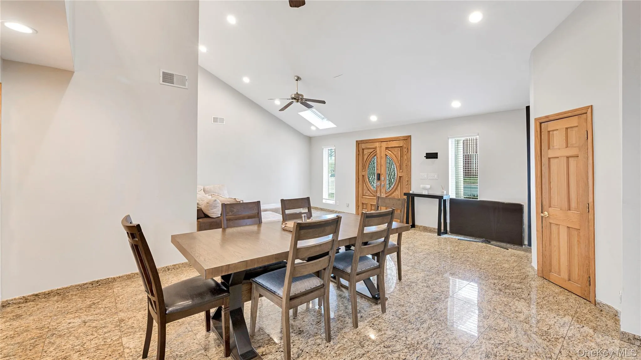 Dining room featuring granite floors, a skylight, recessed lighting, a ceiling fan, and high vaulted ceiling Dining room featuring granite floors, a skylight, recessed lighting, a ceiling fan, and high vaulted ceiling