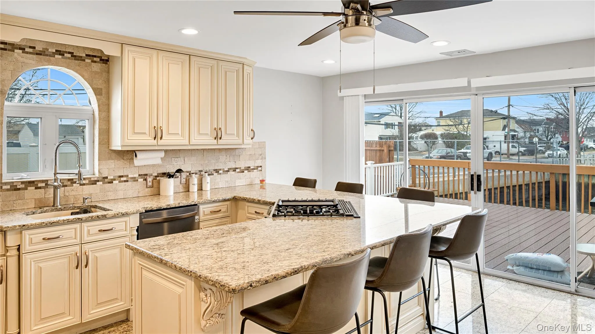 Kitchen with cream cabinets, a kitchen breakfast bar, light stone counters, recessed lighting, and stainless steel dishwasher Kitchen with cream cabinets, a kitchen breakfast bar, light stone counters, recessed lighting, and stainless steel dishwasher