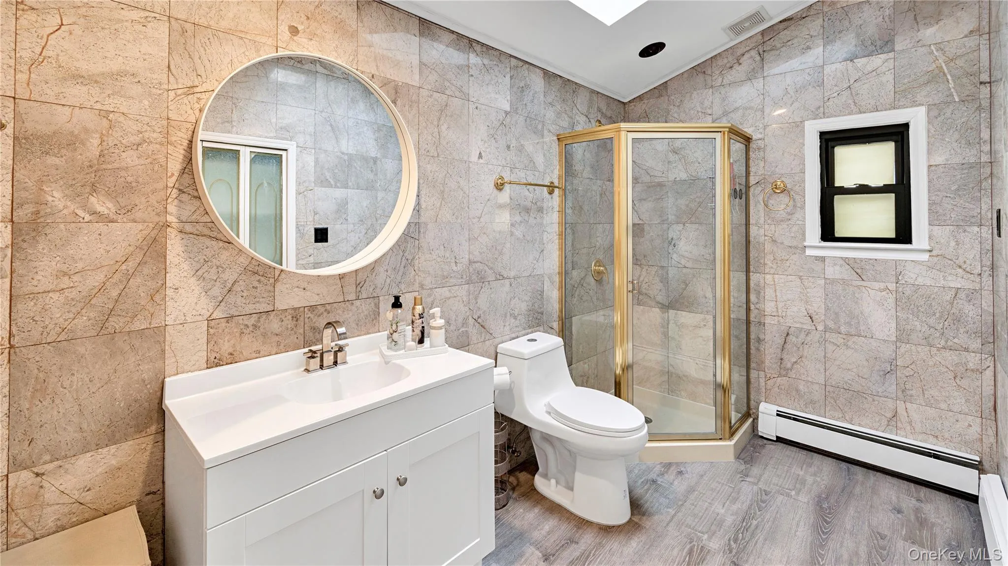 Full bath featuring tile walls, a baseboard radiator, lofted ceiling, vanity, and a shower stall Full bath featuring tile walls, a baseboard radiator, lofted ceiling, vanity, and a shower stall