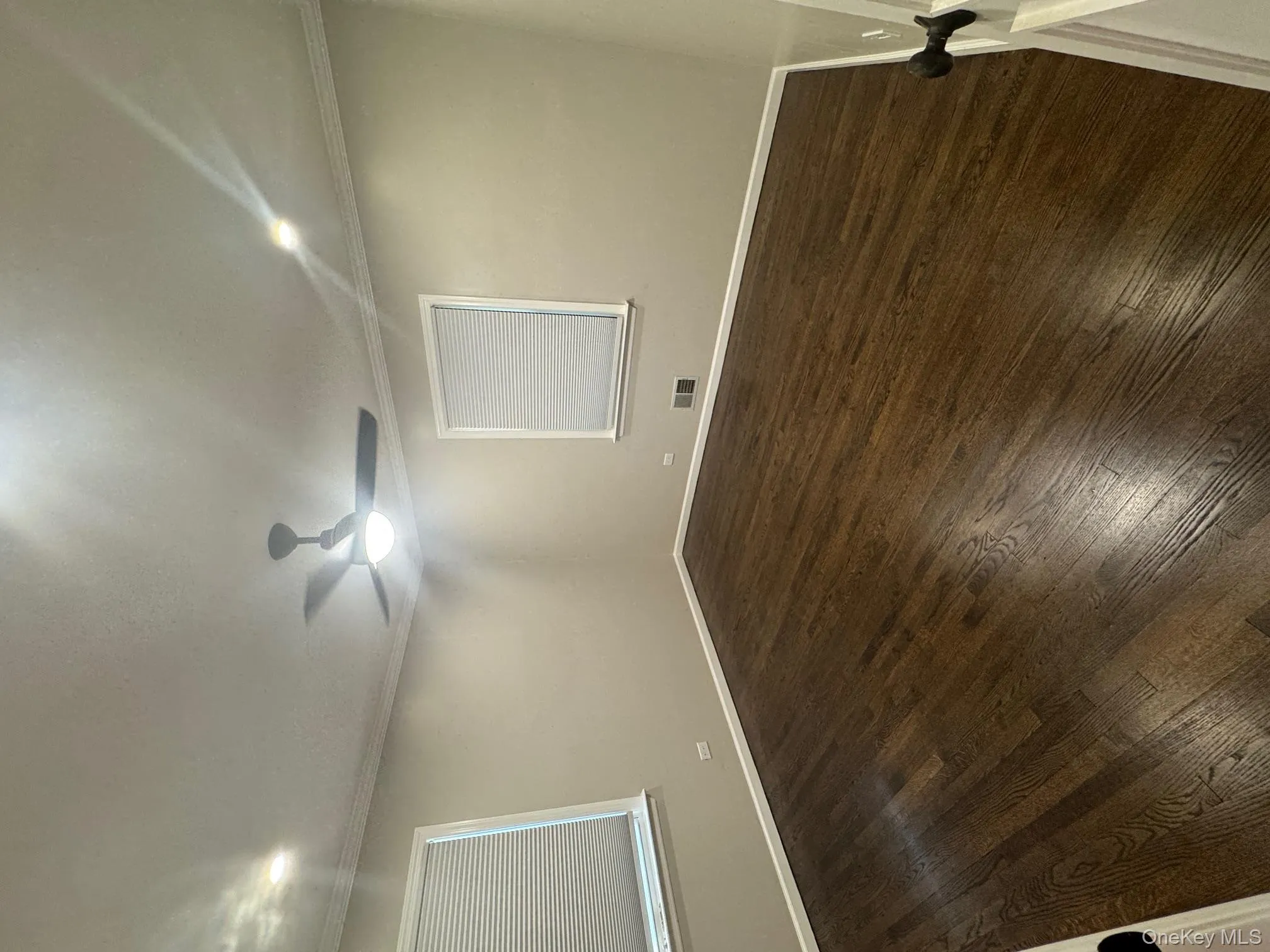 Empty room with ornamental molding, dark wood-style flooring, and recessed lighting Empty room with ornamental molding, dark wood-style flooring, and recessed lighting