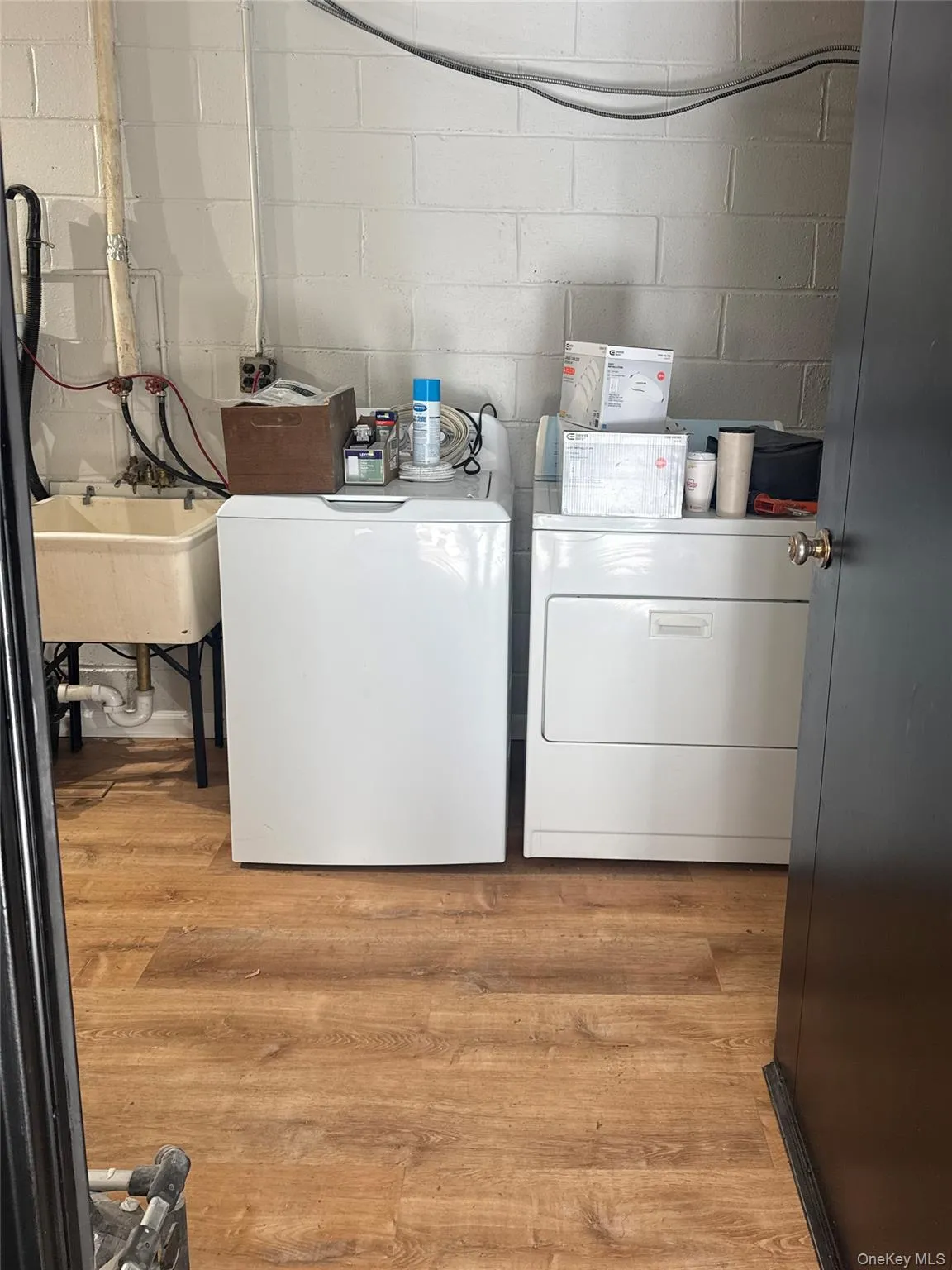 Laundry room featuring concrete block wall, light wood-style floors, and washing machine and dryer Laundry room featuring concrete block wall, light wood-style floors, and washing machine and dryer