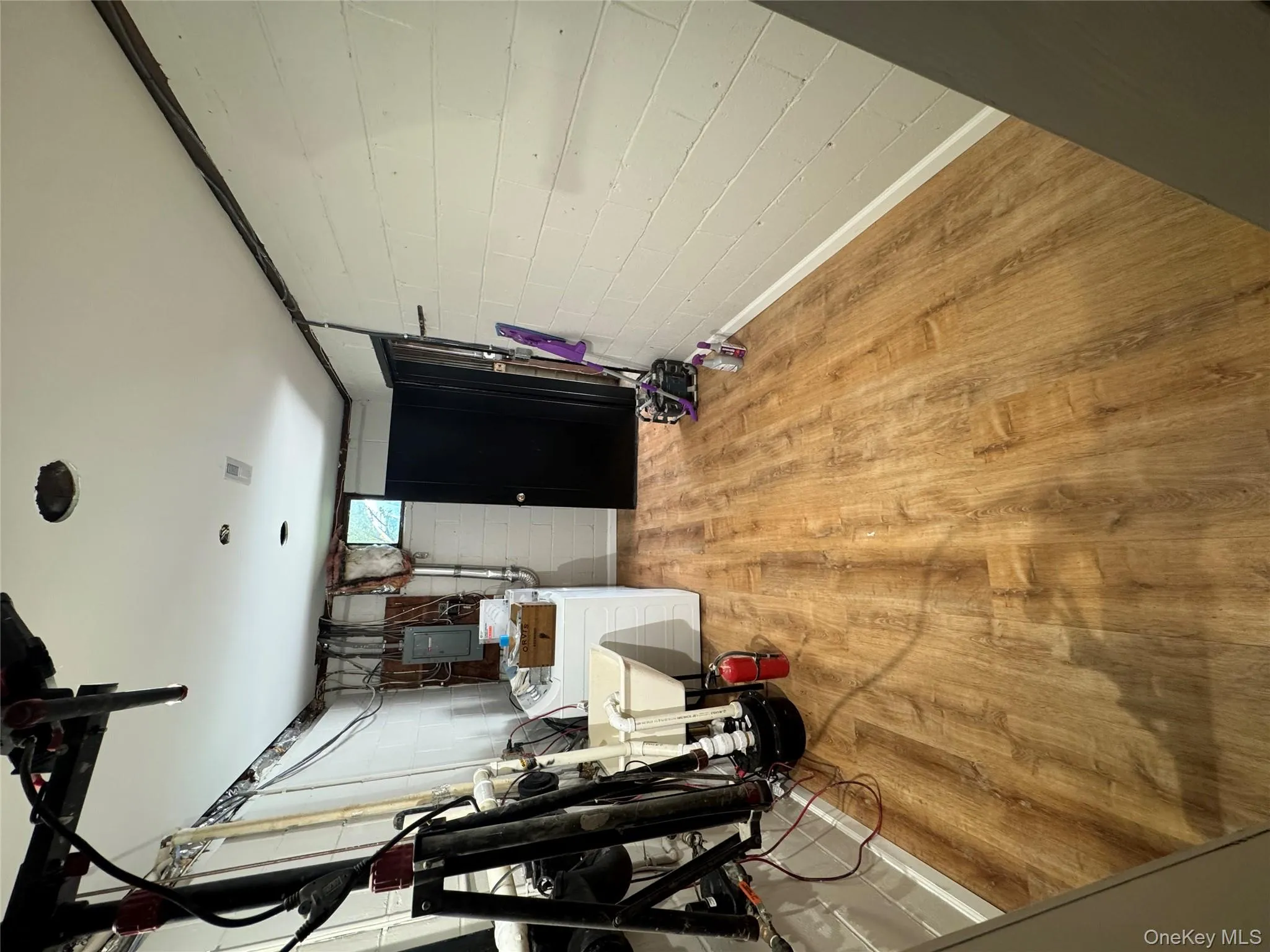 Below grade area with wood finished floors, washing machine and dryer, and electric panel Below grade area with wood finished floors, washing machine and dryer, and electric panel