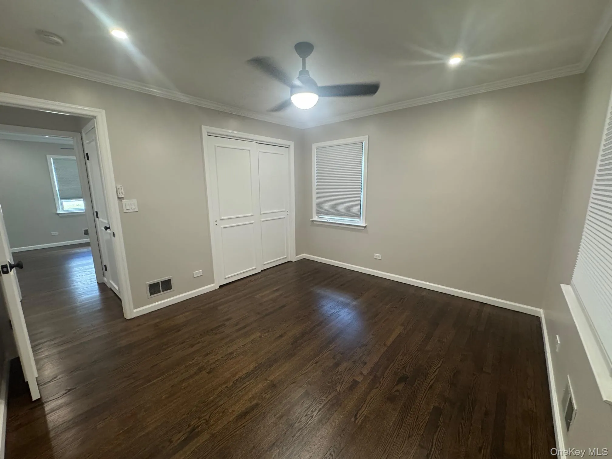 Unfurnished bedroom with dark wood-style flooring, crown molding, a closet, ceiling fan, and recessed lighting Unfurnished bedroom with dark wood-style flooring, crown molding, a closet, ceiling fan, and recessed lighting