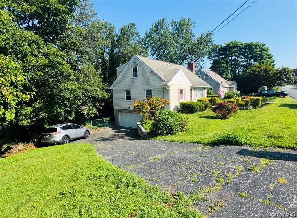 View of side of home with a lawn, driveway, a garage, and a chimney View of side of home with a lawn, driveway, a garage, and a chimney